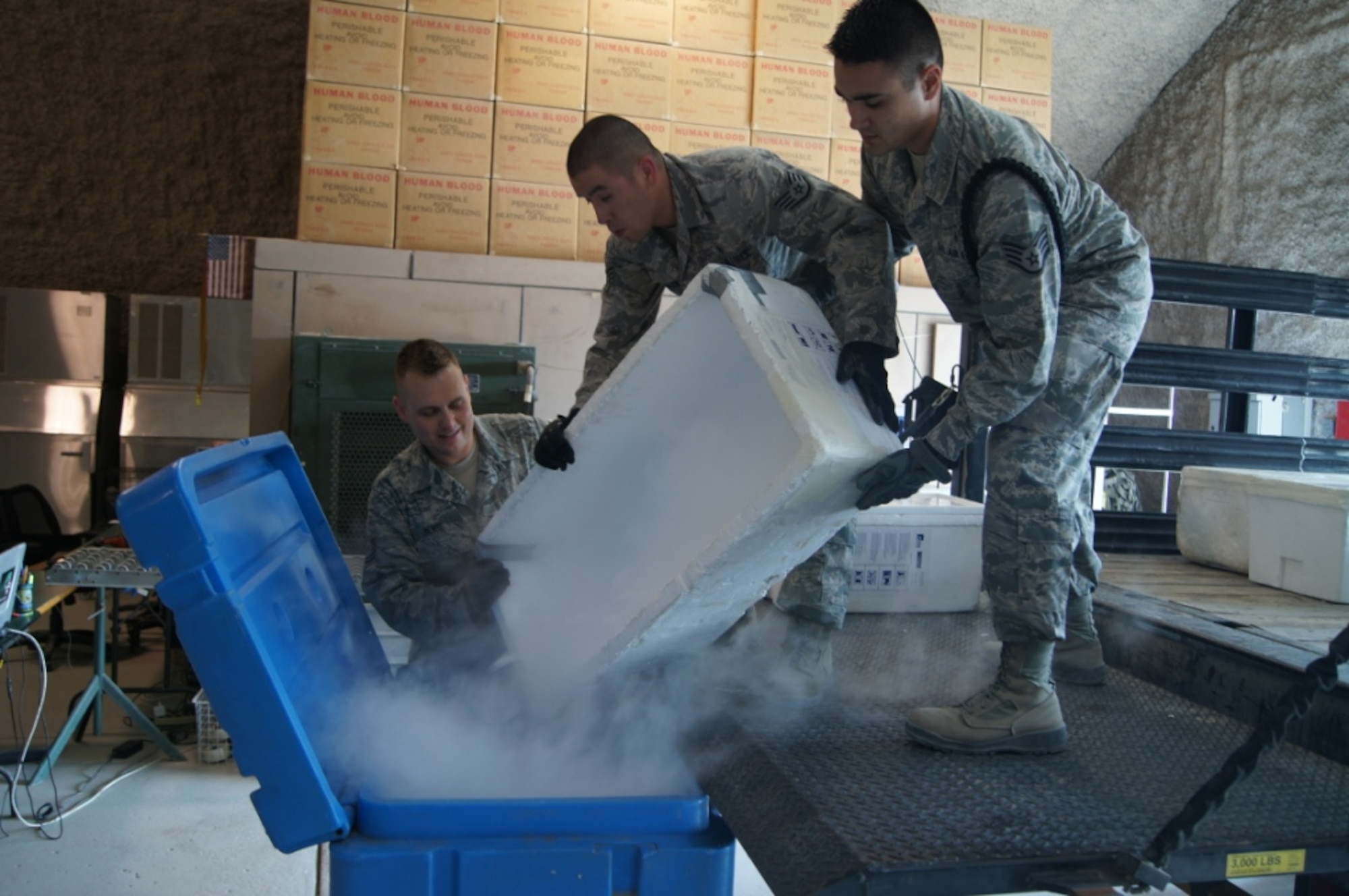 (left to right) Tech. Sgt. Joshua Bense, Staff Sgt. Jorge Rodriguez and Staff Sgt. Rashad El-Jurdi, all 379th Blood Transshipment Center technicians, unload the recently delivered dry ice into a storage bin. The team goes through 3,300 pounds of dry ice every week. The dry ice is used to pack and ship the frozen blood products, giving them a shelf life of 48 hours before the products need to be re-iced. (U.S. Air Force photo/Chief Master Sgt. Lawrence Blake)