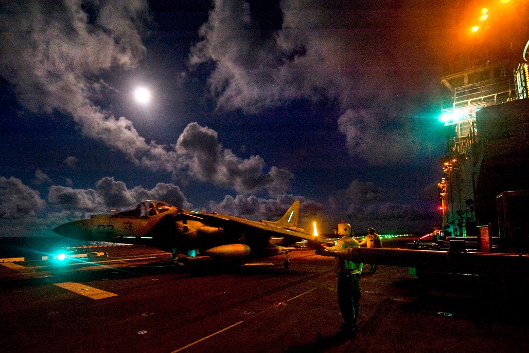 U.S. Navy flight deck personnel taxi an AV-8B Harrier jet aircraft assigned to Marine Attack Squadron 542 across the flight deck during night flight operations aboard the amphibious assault ship USS Bonhomme Richard under way in the Philippine Sea, Aug. 29, 2012. The Bonhomme Richard is the lead ship of the only forward-deployed amphibious assault group.