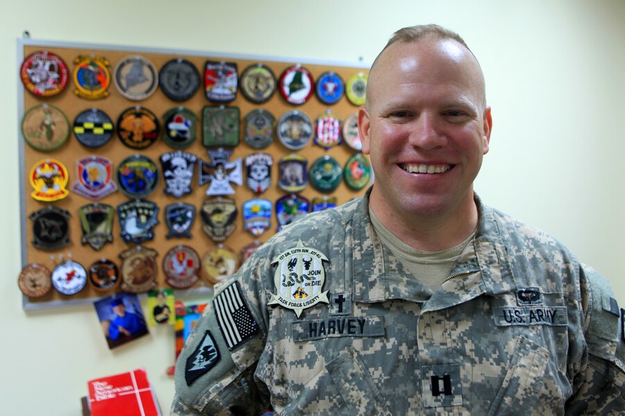 Former Marine and now U.S. Army chaplain, Capt. David Harvey, poses for a photograph in Camp Buehring, Kuwait, Aug. 3, 2012, standing in front of a board full of military patches representing dozens of units that have passed through the camp during his tour. Harvey volunteered to provide chaplain services to Marine Medium Tiltrotor Squadron (VMM) 261 (Reinforced), 24th Marine Expeditionary Unit, while they conducted sustainment training in Kuwait. The 24th MEU is deployed with the Iwo Jima Amphibious Ready Group as a U.S. Central Command theater reserve force providing support for maritime security operations and theater security cooperation efforts in the U.S. 5th Fleet area of responsibility.