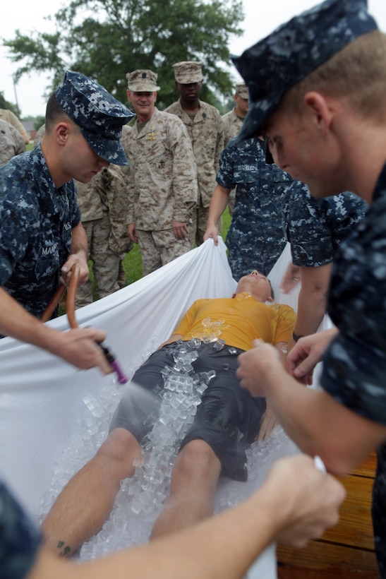 Navy Petty Officer 3rd Class Paul Johnson III is covered in ice and watered as an example victim during the hot weather standard operating procedure training aboard Marine Corps Base Camp Lejeune Aug. 24. Johnson is demonstrating the ‘taco’ method for cooling an individual suffering from a heat related injury.