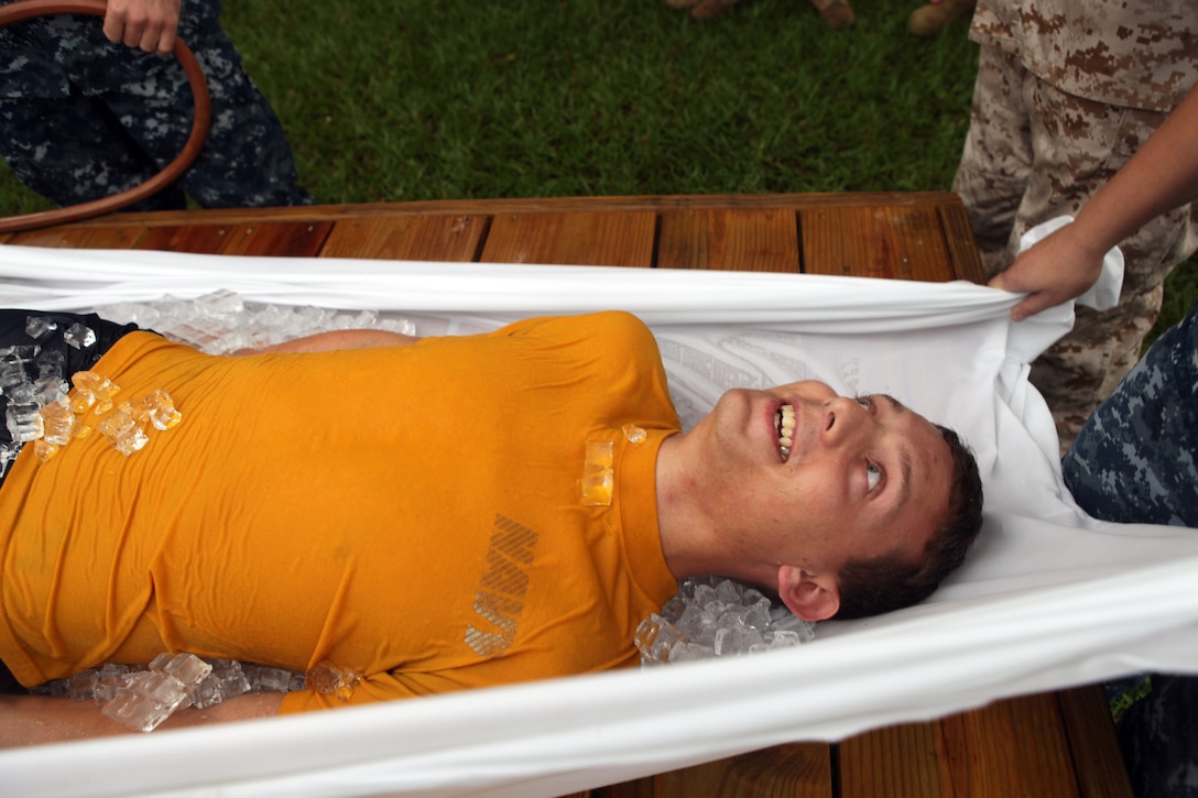 Navy Petty Officer 3rd Class Paul Johnson III is covered in ice and watered down as an example victim during the hot weather standard operating procedure training aboard Marine Corps Base Camp Lejeune Aug. 24. Johnson is demonstrating the ‘taco’ method for cooling an individual suffering from a heat related injury.