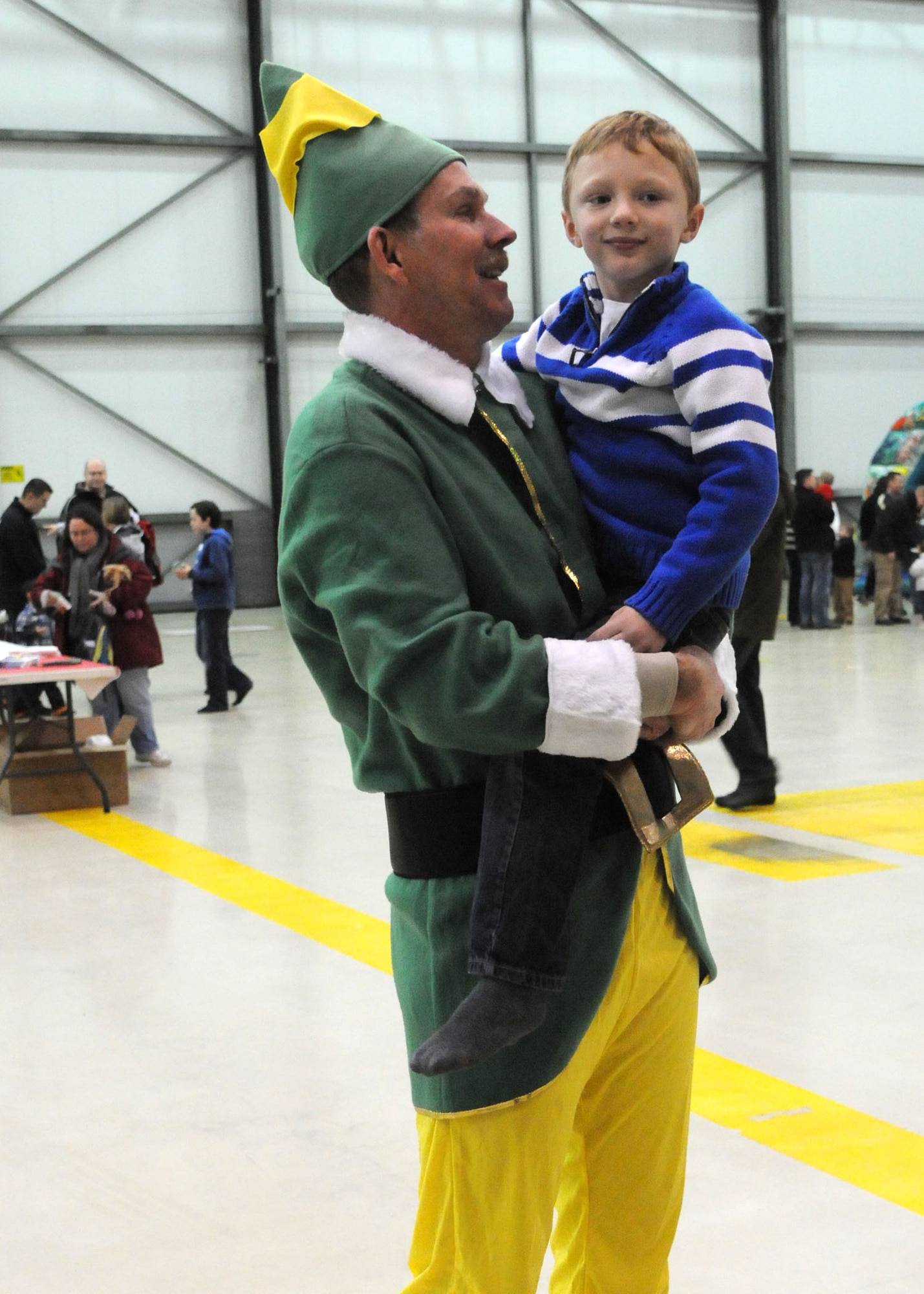 Chief Master Sgt. Christopher Powell, 100th Air Refueling Wing command chief from Fulton Ky., talks to Drake Fewell, 6, son of Staff Sgt. Michel Fewell, 100th Aircraft Maintenance Squadron hydraulics craftsman from Abilene Tx., at the 100th Maintenance Group Children's Christmas Party Dec. 1, 2012, at Hangar 803 at RAF Mildenhall, England. Chief Powell played the role of buddy the elf this year and assisted Santa in speaking to the children and asking them what they wanted for Christmas. . (U.S. Air Force photo by Airman 1st Class Kelsey A.L. Waters/Released)