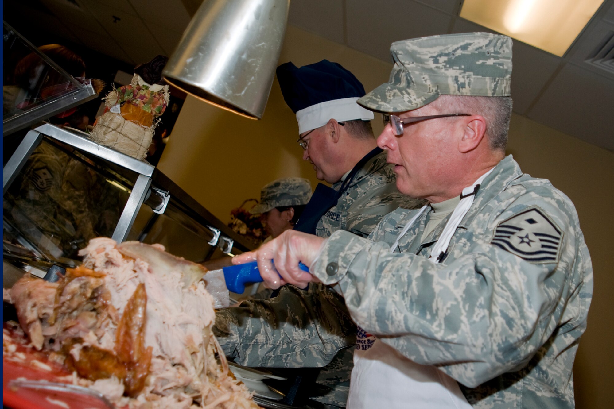 GRISSOM AIR RESERVE BASE, Ind. -- Master Sgt. William Hurley , 434th Communications Squadron first sergeant, carefully carves out slices of turkey next to Lt. Col. Bryan Runion, 434th Logistics Readiness Squadron commander,  during a special holiday meal. Senior leadership from the 434th Air Refueling Wing rolled up their sleeves to serve the annual holiday meal to Airmen during a recent Unit Training Assembly. (U.S. Air Force photo/Senior Airman Jami K. Lancette)