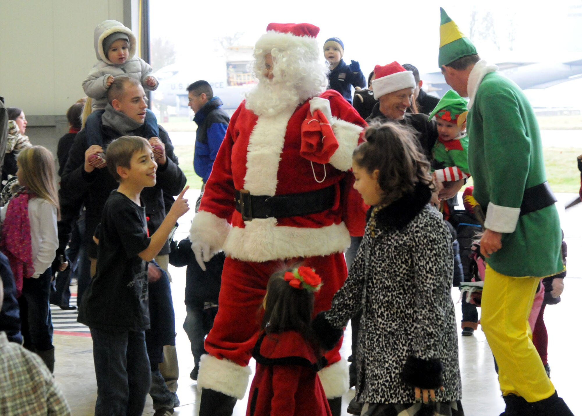 Children greet Santa and his Elf Buddy as they enter Hangar 803 during the 100th Maintenance Group Children's Christmas Party Dec. 1, 2012, at RAF Mildenhall, England. Much to the excitement of the children at the party, Santa and Buddy arrived in a KC-135 Stratotanker. . (U.S. Air Force photo by Airman 1st Class Kelsey A.L. Waters/Released)