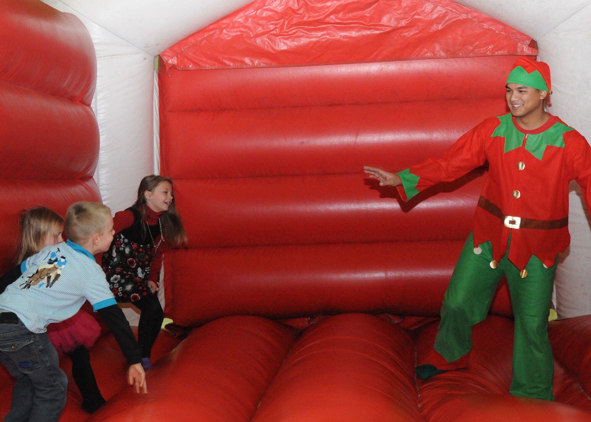 Airman 1st Class Michael Engen, 100th Operations Support Squadron aircrew flight equipment journyman from Owatonna, Minn., jumps in a bouncy castle with children from the 100th Maintenance Squadron Dec. 1, 2012, at Hangar 803 at RAF Mildenhall, England during the 100th Maintenance Group Children's Christmas Party. The party had many activities including cookie decorating, bingo, face painting, coloring and a meet and greet with Santa, who arrived in a KC-135 Stratotanker. (U.S. Air Force photo by Airman 1st Class Kelsey Waters/Released)