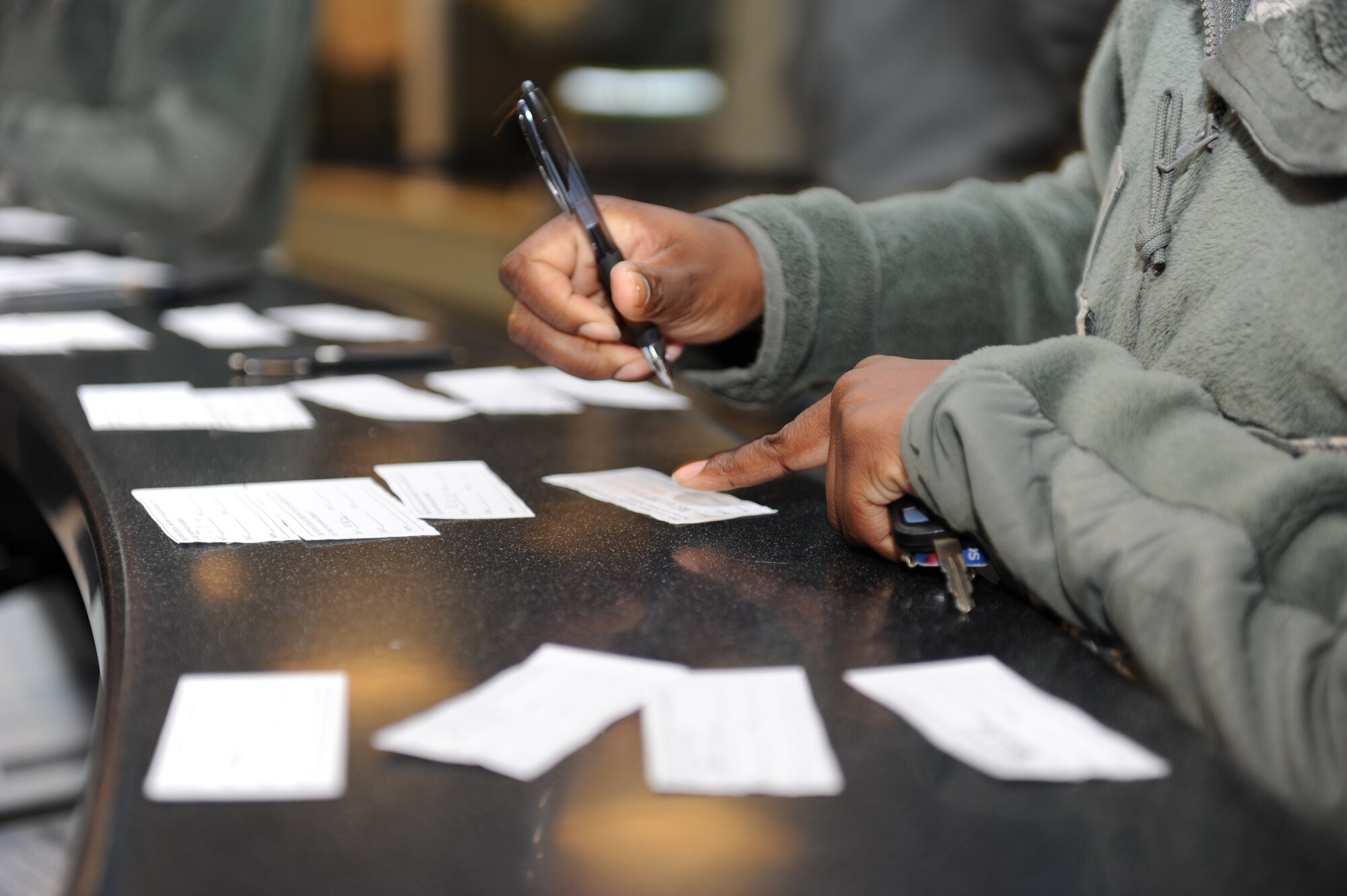 U.S. Air Force members of the 35th Fighter Wing sign accountability cards before processing through the transition area during a phase II Operational Readiness Exercise at Misawa Air Base, Japan on Dec. 3, 2012. OREs test the combat readiness of the wing and its ability to execute assigned missions and tasks.  (U.S. Air Force Photo by Airman 1st Class Kia Atkins)