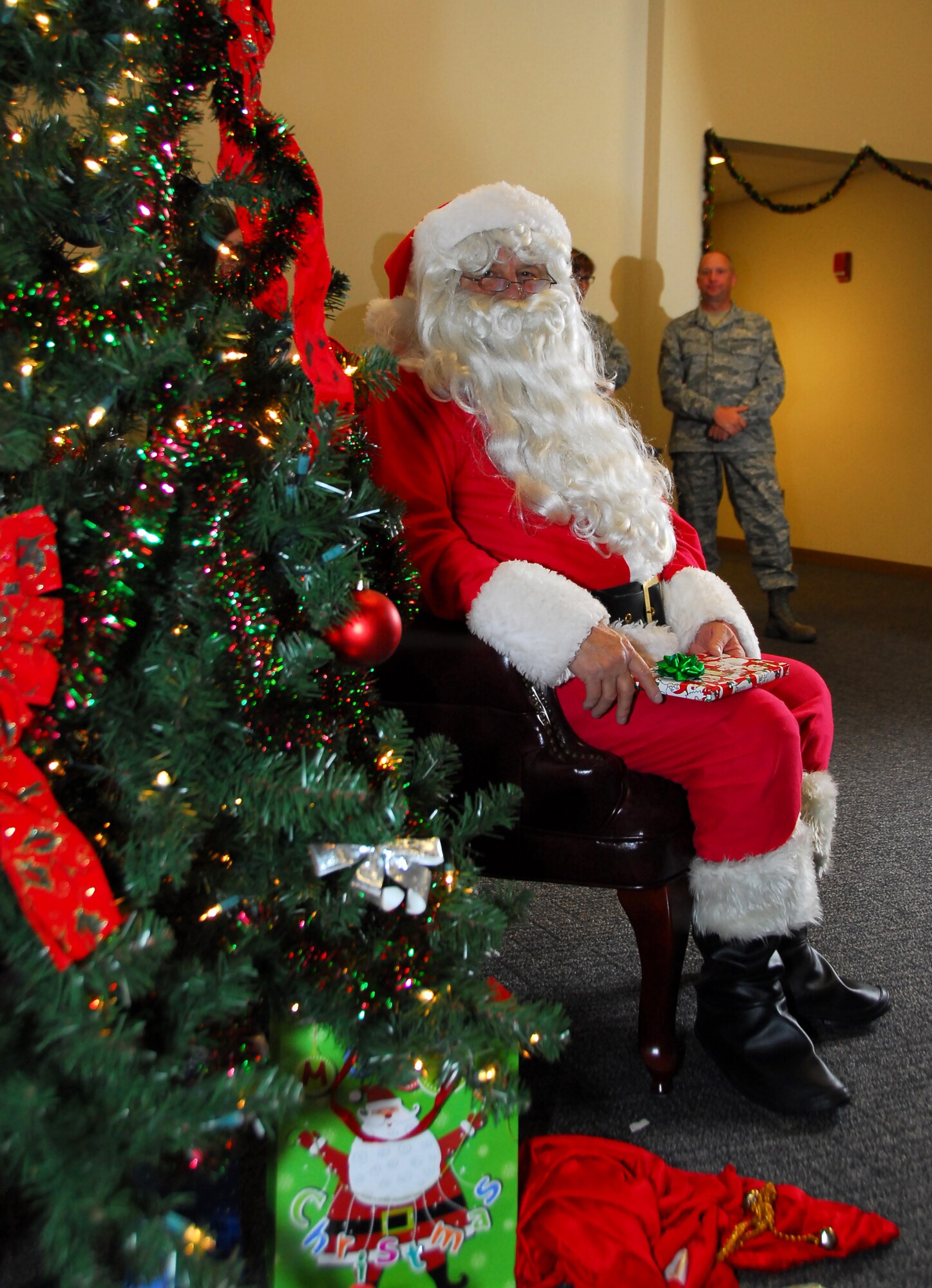 Santa Claus sits beside a Christmas tree in the Roberts Maintenance Facility auditorium at Keesler Air Force Base, Miss., Dec. 1, 2012.  Santa Claus arrived via a 53rd Weather Reconnaissance Squadron WC-130J to hand out gifts to children of 403rd Wing servicemembers.  (U.S. Air Force Photo by Tech. Sgt. Jessica Kendziorek)