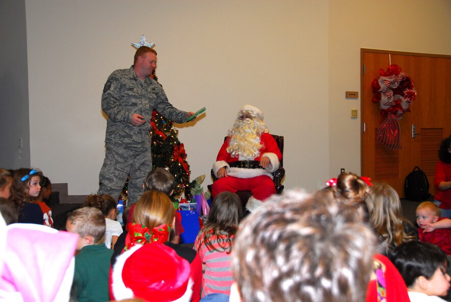 Master Sgt. Brian J. Lamar, 403rd Wing Public Affairs Office, assists Santa Claus at the Roberts Maintenance Facility at Keesler Air Force Base, Miss., Dec. 1, 2012.  Santa Claus handed out presents to children of 403rd Wing servicemembers.  (U.S. Air Force Photo by Tech. Sgt. Jessica L. Kendziorek)