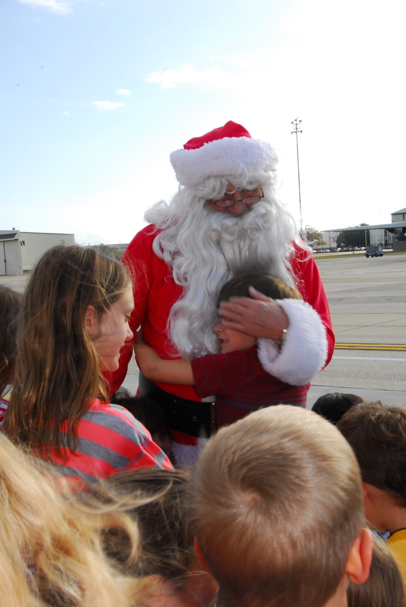 Santa Claus hugs children on the flightline behind the Roberts Maintenance Facility at Keesler Air Force Base, Miss., Dec. 1, 2012.  Santa Claus arrived via a 53rd Weather Reconnaissance Squadron WC-130J to hand out gifts to children of 403rd Wing servicemembers.  (U.S. Air Force Photo by Tech. Sgt. Jessica L. Kendziorek)