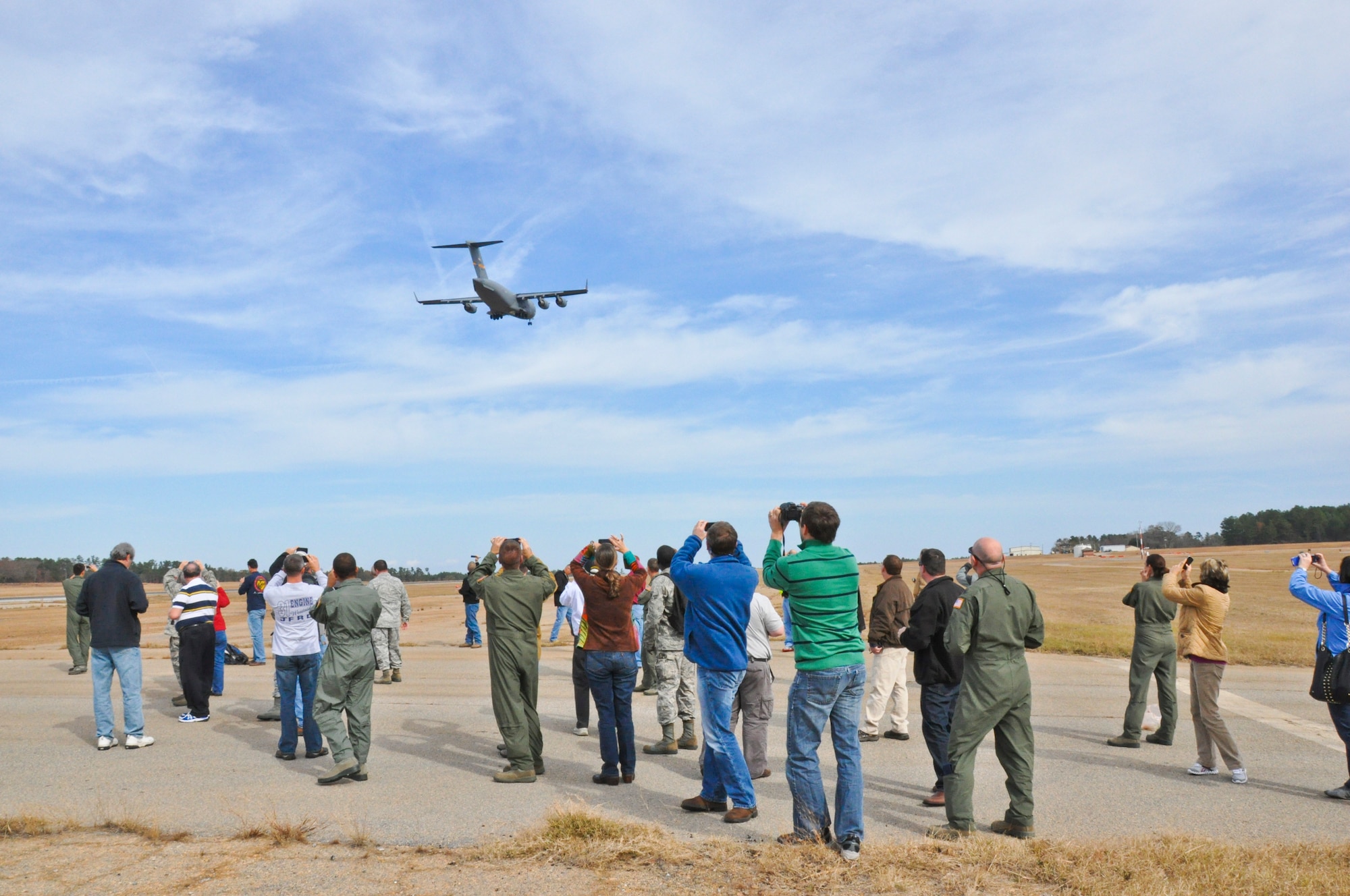 Members of an employer/civic leader flight take pictures of a C-17 Globemaster III flying overhead Saturday Dec. 1, 2012, from the ground at North Auxiliary Field, located in North, S.C.. The leaders took part in the 315th Airlift Wing's employer tour flight, which is designed to orient employers with the mission of the Air Force Reserve.  (U.S. Air Force photo by 1st Lt. Jeff Kelly)