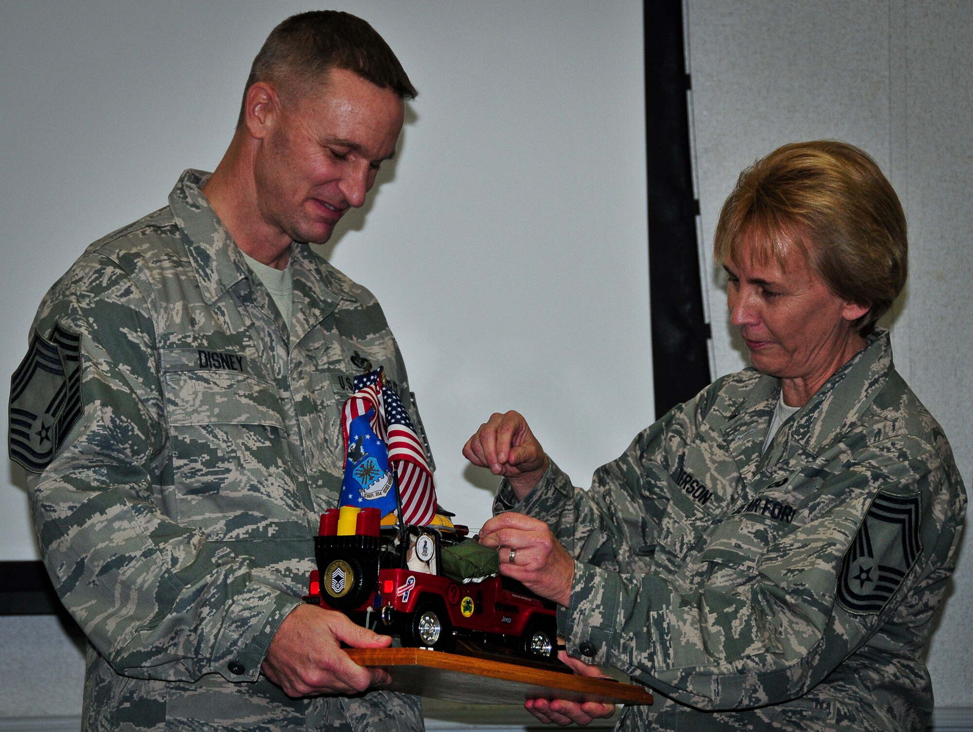 Chief Master Sgt. Michael Disney, of the 919th Civil Engineer Squadron, accepts the Jeep from Chief Master Sgt. Darlene Peterson as the newest chief during his induction ceremony at Duke Field, Fla. Dec. 1.  Following Air Force tradition, Disney must not relinquish control of the toy Jeep memento until the next new chief is inducted.  (U.S. Air Force photo/Tech. Sgt. Jon McCallum)