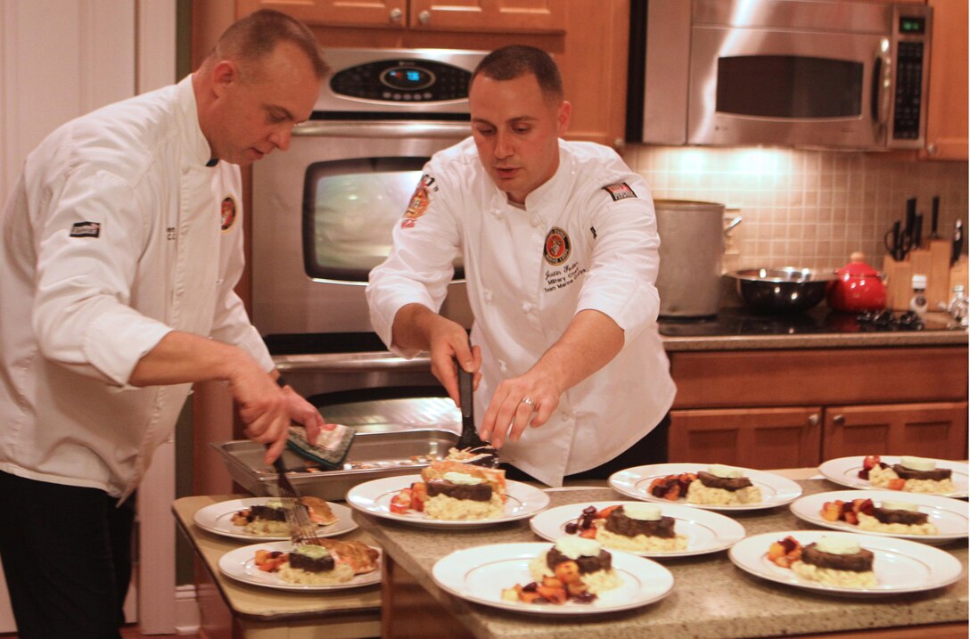 Master Sgt. T.J. Hansen and Staff Sgt. Justin Fedin, II Marine Expeditionary Force commanding general's aids, place salmon onto remaining dinner plates during II Marine Expeditionary Force Heroes Dinner held at Maj. Gen. Raymond C. Fox's home aboard Marine Corps Base Camp Lejeune, Nov. 14. The Marines worked with celebrity chef, Rick Tarantino, to complete a four-course dinner for Marines and sailors being honored for their selflessness and courage.