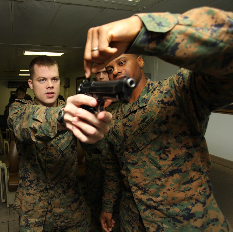 USS IWO JIMA, Mediterranean Sea (Nov. 30, 2012) - Lance Cpl. Dustan Myers(left), a Gainsville, Ga., native and radio operator, and Gunnery Sgt. Domicas Perdue(right), a Tyler, Texas, native and combat marksmanship instructor, both with the Command Element, 24th Marine Expeditionary Unit, practice the basics of M9 pistol marksmanship aboard USS Iwo Jima, Nov. 30, 2012. Combat marksmanship training is a continuous part of life for Marines, no matter what their military occupational specialty is, and regardless of whether they're stateside or deployed on a ship. The 24th Marine Expeditionary Unit is deployed with the Iwo Jima Amphibious Ready Group in the 6th Fleet area of responsibility serving as an expeditionary crisis response force capable of a variety of missions, from full-scale combat to evacuations and humanitarian assistance. Since deploying in March, they have supported a variety of missions in the U.S. Central, Africa and European Commands, assisted the Navy in safeguarding sea lanes, and conducted various bilateral and unilateral training events in several countries in the Middle East and Africa. (U.S. Marine Corps photo by Lance Cpl. Tucker S. Wolf/Released)