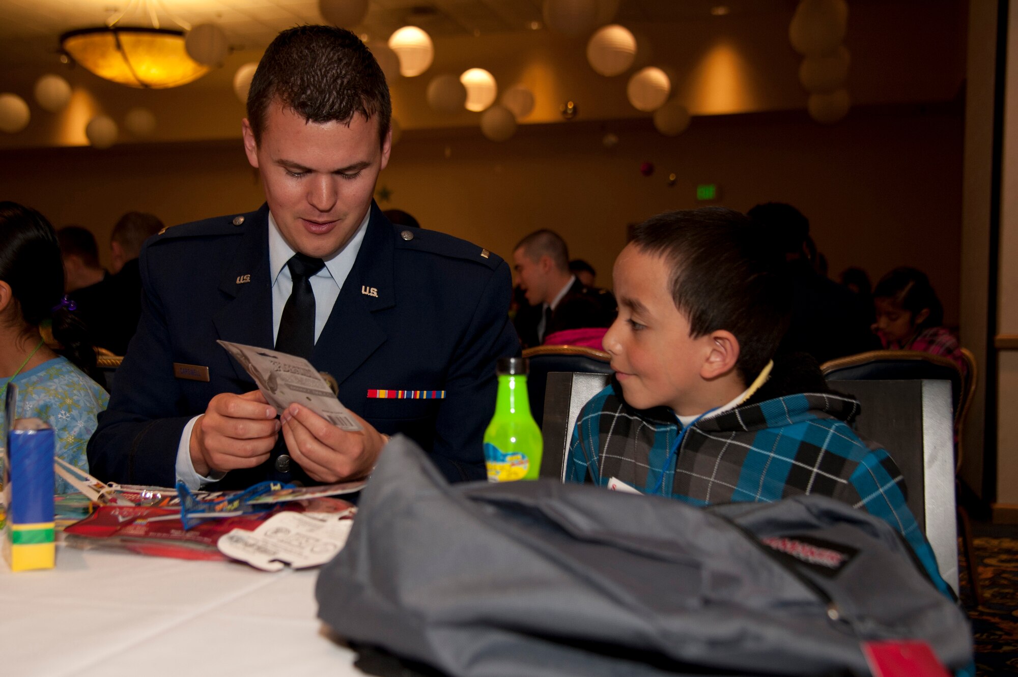 VANDENBERG AIR FORCE BASE, Calif. – Lt. Adam Carsdale, a student from the 532nd Training Squadron, looks through the goodies in Jose Cazares’, age 7 from the Santa Maria area, backpack during the Operation Kids Christmas event at the Pacific Coast Club here Saturday, Dec. 12, 2012. OKC is an annual event, organized and run by a private organization, in which almost 200 local children are brought on base and given the opportunity to play games, meet Santa and enjoy the companionship of volunteer military members. (U.S. Air Force photo/Senior Airman Lael Huss)