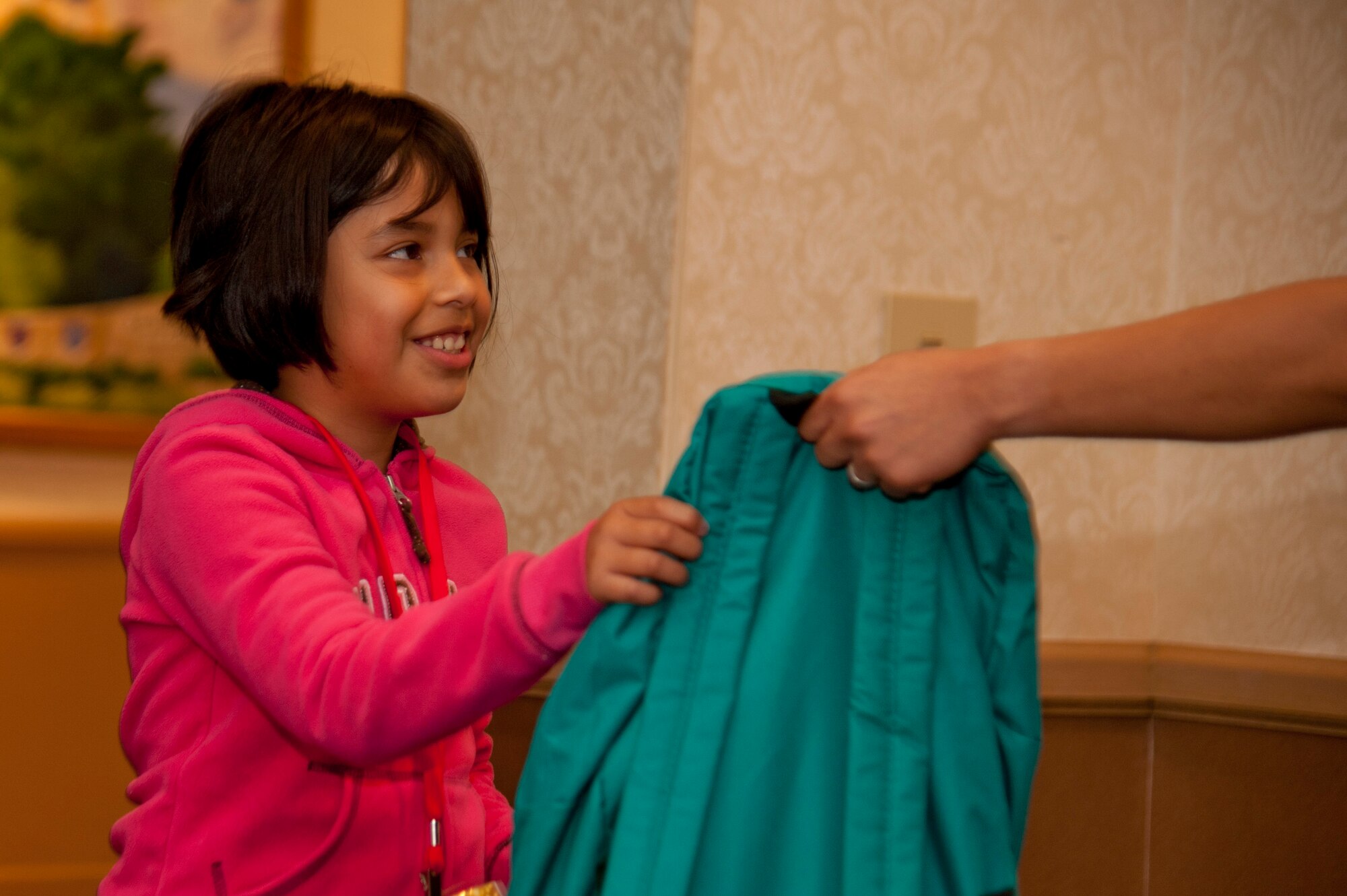 VANDENBERG AIR FORCE BASE, Calif. – Carla Sixto, 9 year old from the Lompoc area, receives a blue backpack full of goodies from a volunteer while on her way to the ballroom for the Operation Kids Christmas event at the Pacific Coast Club here Saturday, Dec. 1, 2012. OKC is an annual event, organized and run by a private organization, in which nearly 200 local children are brought on base and given the opportunity to play games, meet Santa and enjoy the companionship of volunteer military members. (U.S. Air Force photo/Senior Airman Lael Huss)