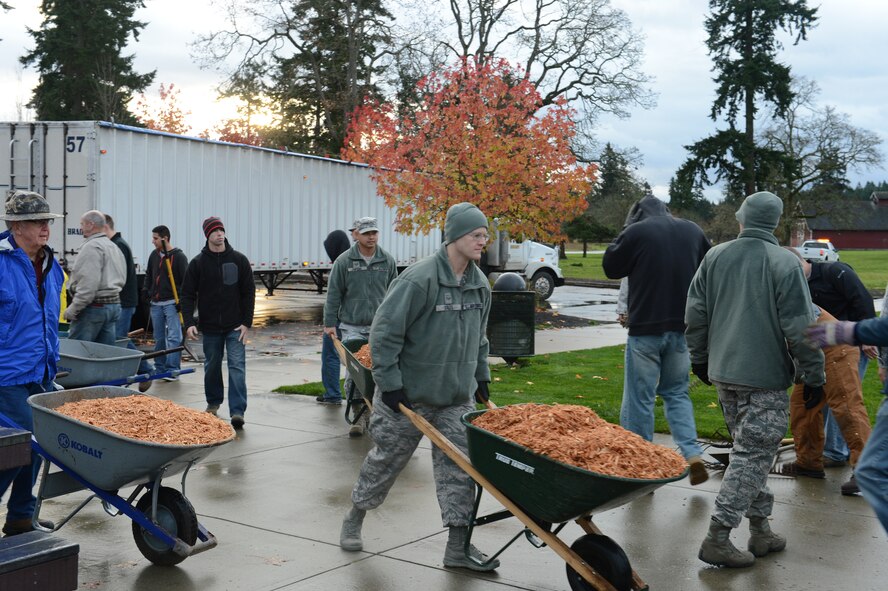 Airmen from the 62nd Airlift Wing, the 627th Air Base Group, and the Western Air Defense Sector, from Joint Base Lewis-McChord, Wash., along with members of the Rotary Club, transport wood chips to the playground, Nov. 30, 2012, at Ft. Steilacoom Park in Lakewood, Wash. The wood chips provide a soft cushion for the children using the jungle gym equipment. (U.S. Air Force photo/Staff Sgt. Sean Tobin)