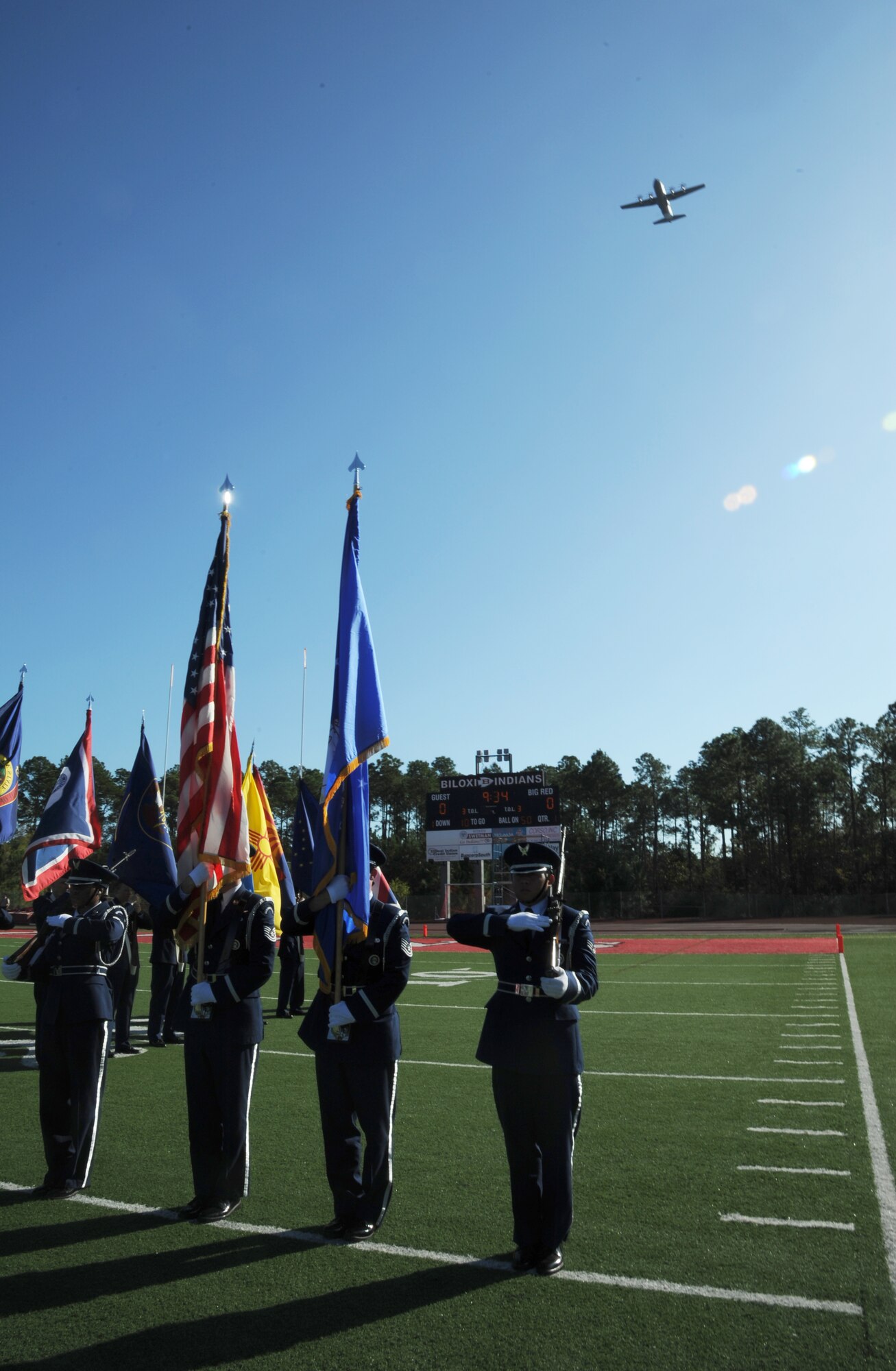 The Keesler Honor Guard prepares to present the colors for the Nation Anthem as a C-130J aircraft belonging to the 403rd Wing, Keesler Air Force Base, Miss., conducts a fly over during the pre-game celebration at the 2012 Mississippi Bowl at the Biloxi High School football stadium Dec. 2, 2012.  Other Keesler participation included a 50-State flag team and a drill down performance by the 81st Training Group.  (U.S. Air Force photo by Kemberly Groue)
