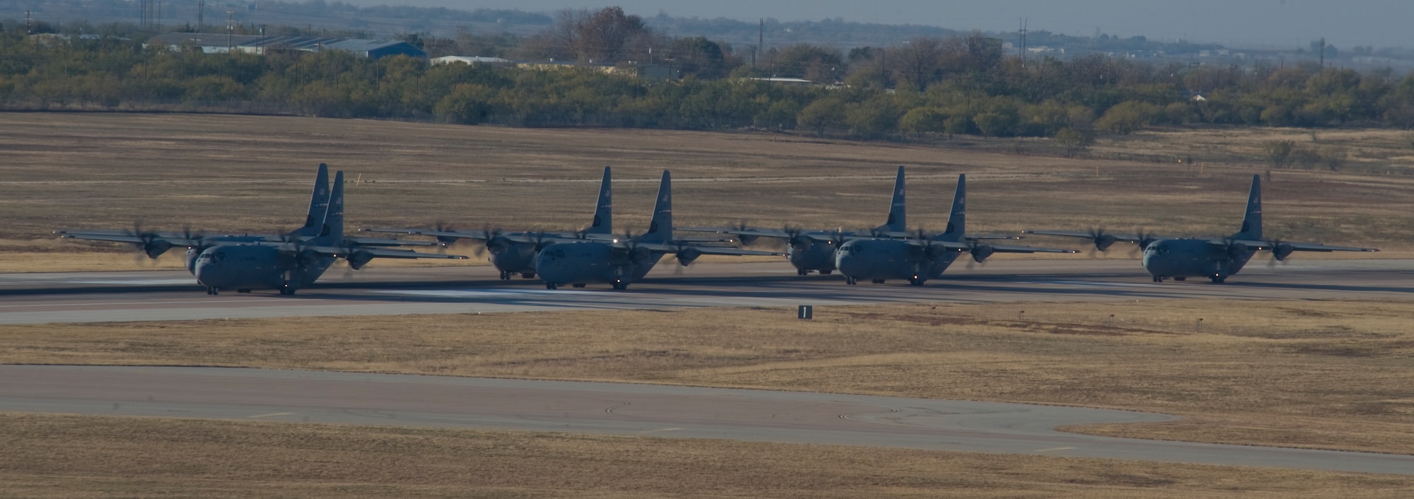 Seven C-130Js prepare to take off during a training exercise Nov. 30, 2012, at Dyess Air Force Base, Texas. The C-130J incorporates state-of-the-art technology to reduce manpower requirements, lower operating and support costs, and provides life-cycle cost savings over earlier C-130 models. Compared to older C-130s, the J model climbs faster and higher, flies farther at a higher cruise speed, and takes off and lands in a shorter distance. Dyess has received 23 J models and is scheduled to get a total of 28, making it the largest C-130J unit in the world. (U.S. Air Force photo by Staff Sgt. Richard P. Ebensberger/ Released)