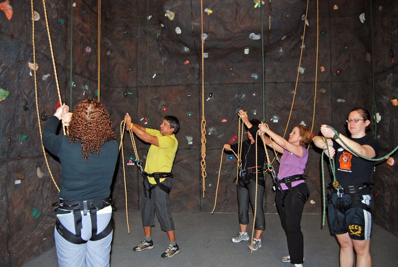 A class learns how to properly tie a knot to their harness before rock climbing during a certification class Oct. 14. Classes are offered every second Tuesday at 5 p.m. and every second Wednesday at 11:30 a.m. Once individuals are certified, they may use the rock climbing wall at the Peterson Sports and Fitness Center any time, free of charge. (U.S. Air Force photo/Lea Johnson)