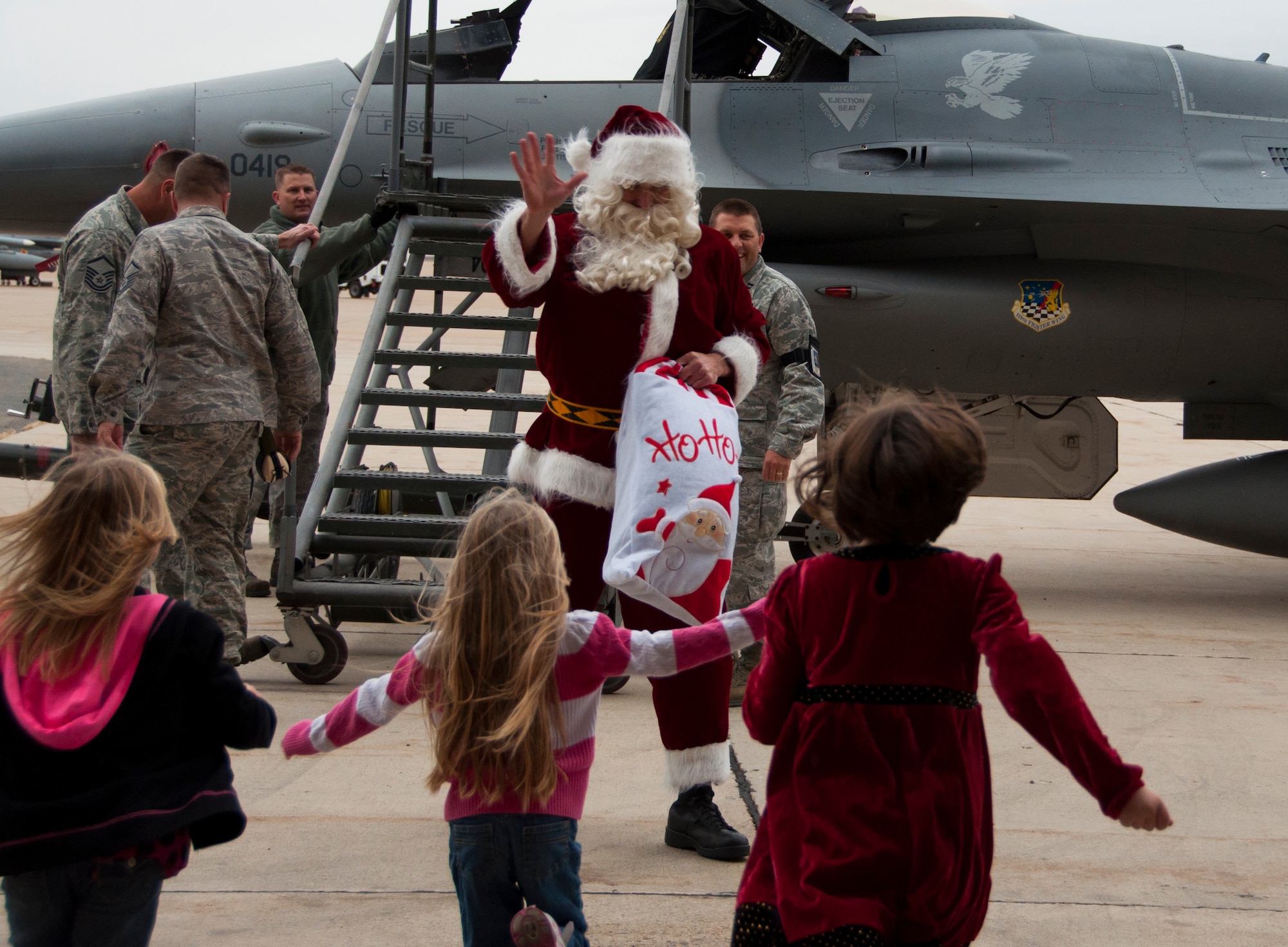 Children run to greet Santa as he steps off the F-16 to deliver gifts during the wing’s Christmas party here Dec. 2. 419th maintenance personnel towed the F-16 near the hangar where the children waited for Santa’s arrival. (U.S. Air Force photo/Senior Airman Crystal Charriere)