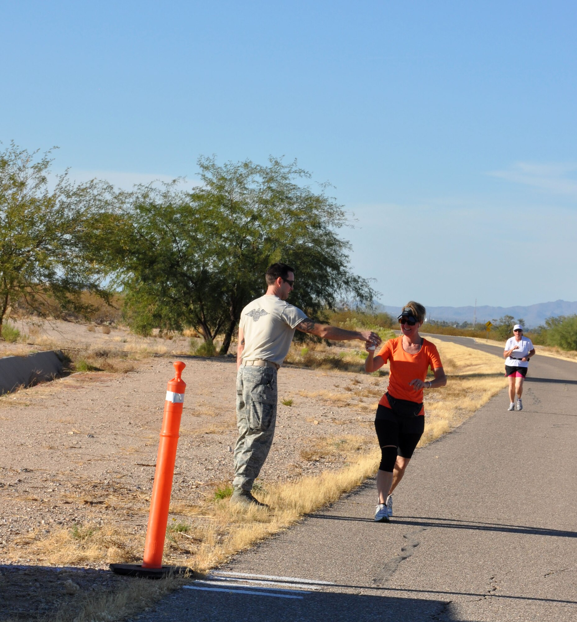 Lt. Col. Conley Titus, clinical nurse with the 943rd Aerospace Medical Squadron receives water at an aid station during the first ever 943rd Rescue Group Holiday Fun Run. The fun run consisted of a five or 10 kilometer run and t-shirts were awarded to the top finishers of each race. (U.S. Air Force Photo/ Staff Sgt. Sarah Pullen)