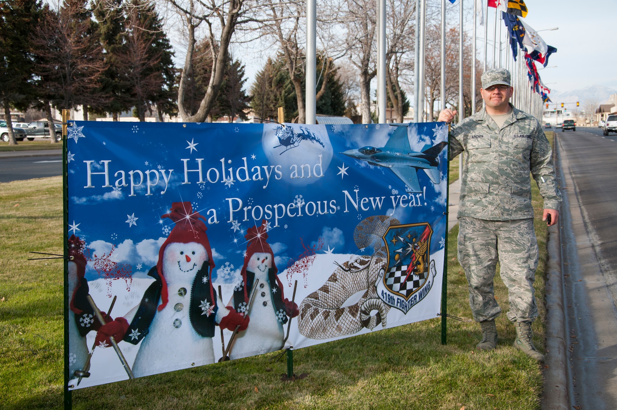 Staff Sgt. Henry Archer, intelligence journeyman in the 419th Operations Group, stands beside the greeting card he designed to spruce up the base’s Christmas Card Lane. Each year organizations across Hill make giant Christmas cards, which are displayed along  Southgate Avenue throughout December. Archer spent about 16 hours on the project. He said it was a creative way to say thanks and "happy holidays" to everyone who serves in the military. (Courtesy photo)