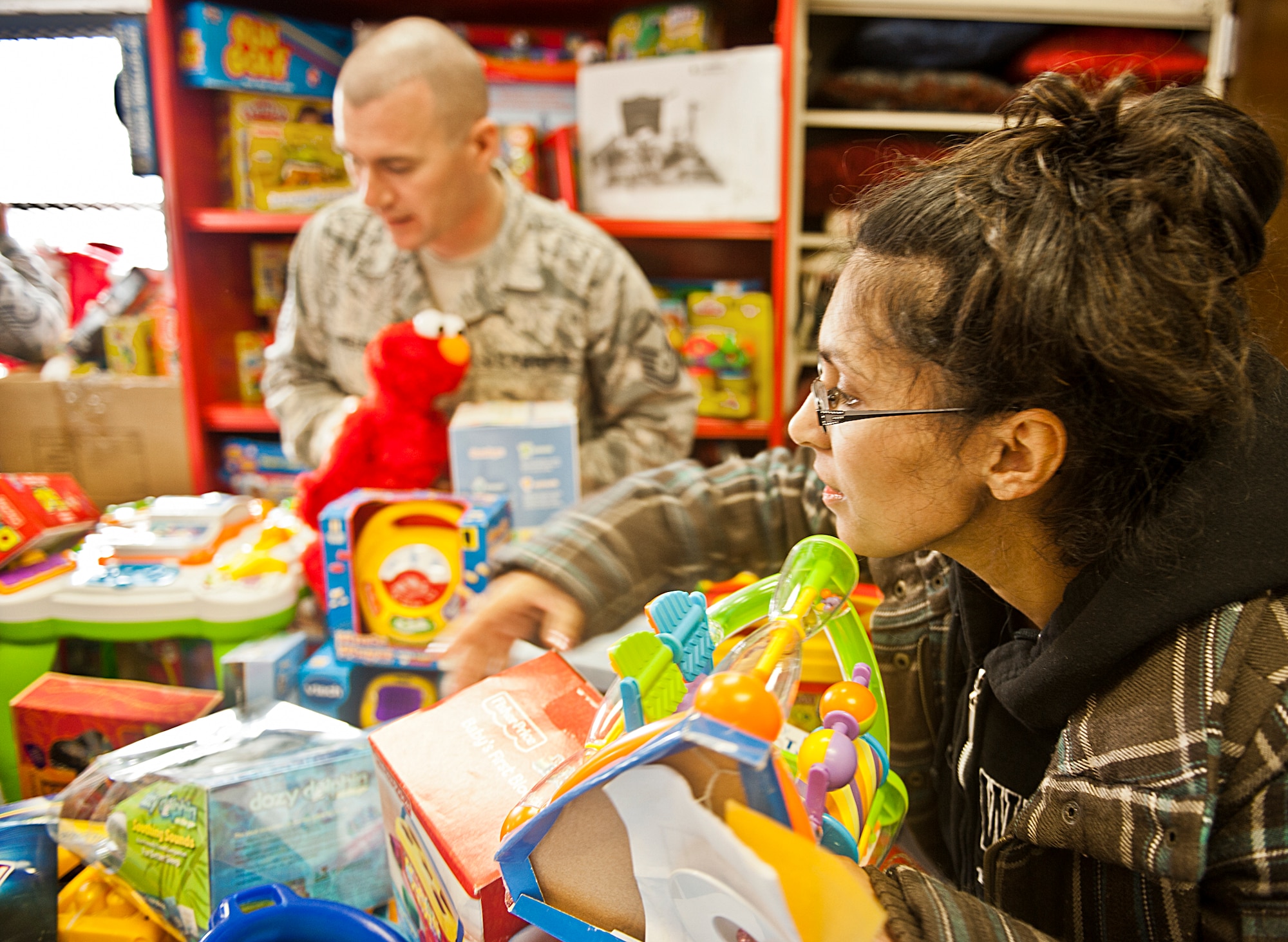 Rebecca Coates gets help finding toys from a volunteer service member during the 9th annual toy distribution at Eglin Air Force Base, Fla. Nov. 29.  More than 6,000 toys, collected by donations to the Airman’s Attic made throughout the year, were distributed by volunteers to active-military families in need of assistance during the holidays. (U.S. Air Force photo/Randy Gon)