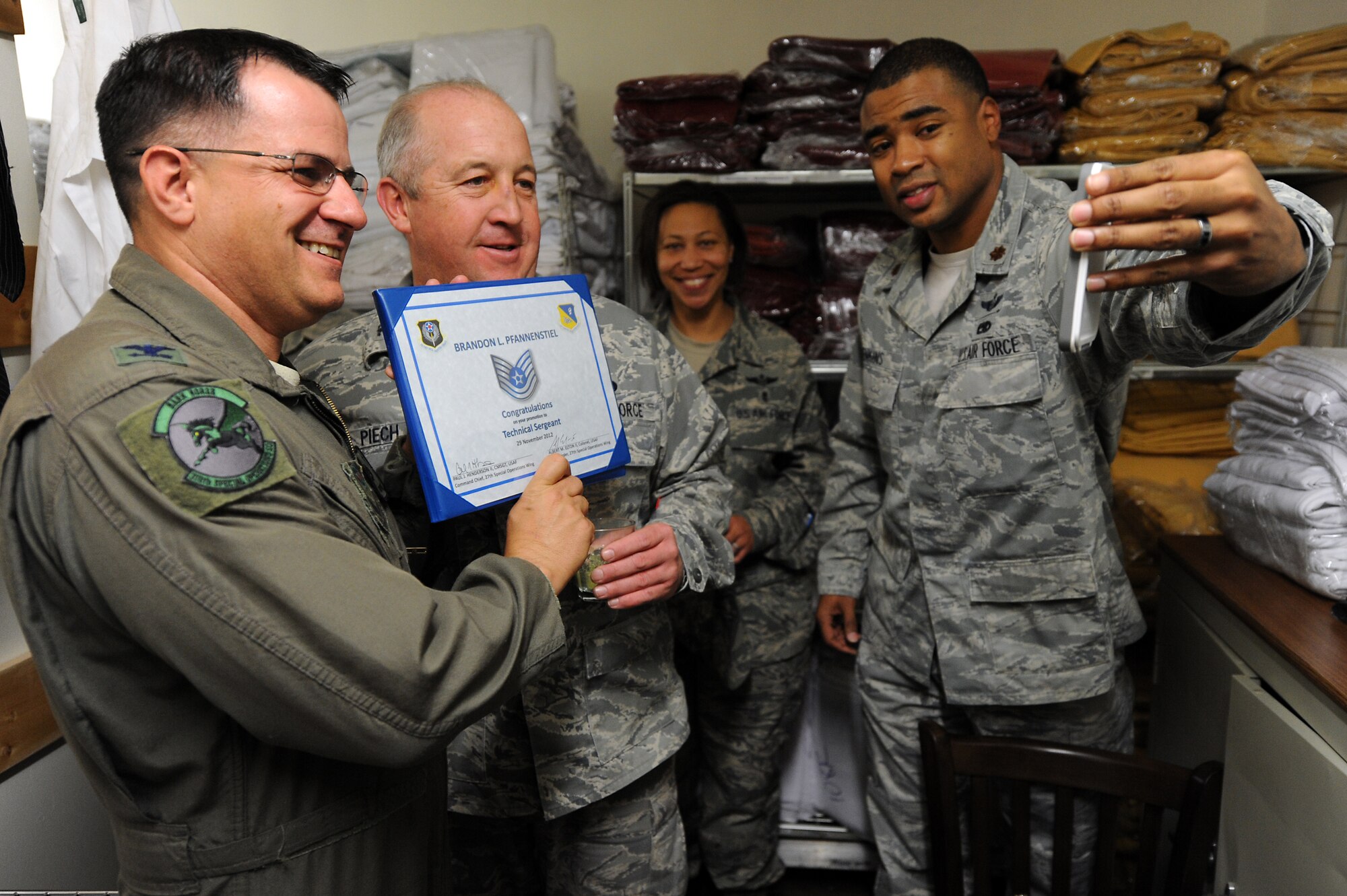 U.S. Air Force Col. Buck Elton, 27th Special Operations Wing commander, and Col. David Piech, 27th Special Operations Mission Support Group commander, present Staff Sgt. Brandon Pfannenstiel, 27th Special Operations Civil Engineer Squadron Explosive Ordnance Disposal technician, with a certificate congratulating him on a Stripes for Exceptional Performers promotion, Nov. 29,2012.  Because Pfannenstiel was away preparing to deploy, leadership from Cannon Air Force Base, N.M., used Facetime to award this new Tech. Sgt. his stripes. (U.S. Air Force photo/Senior Airman Jette Carr)