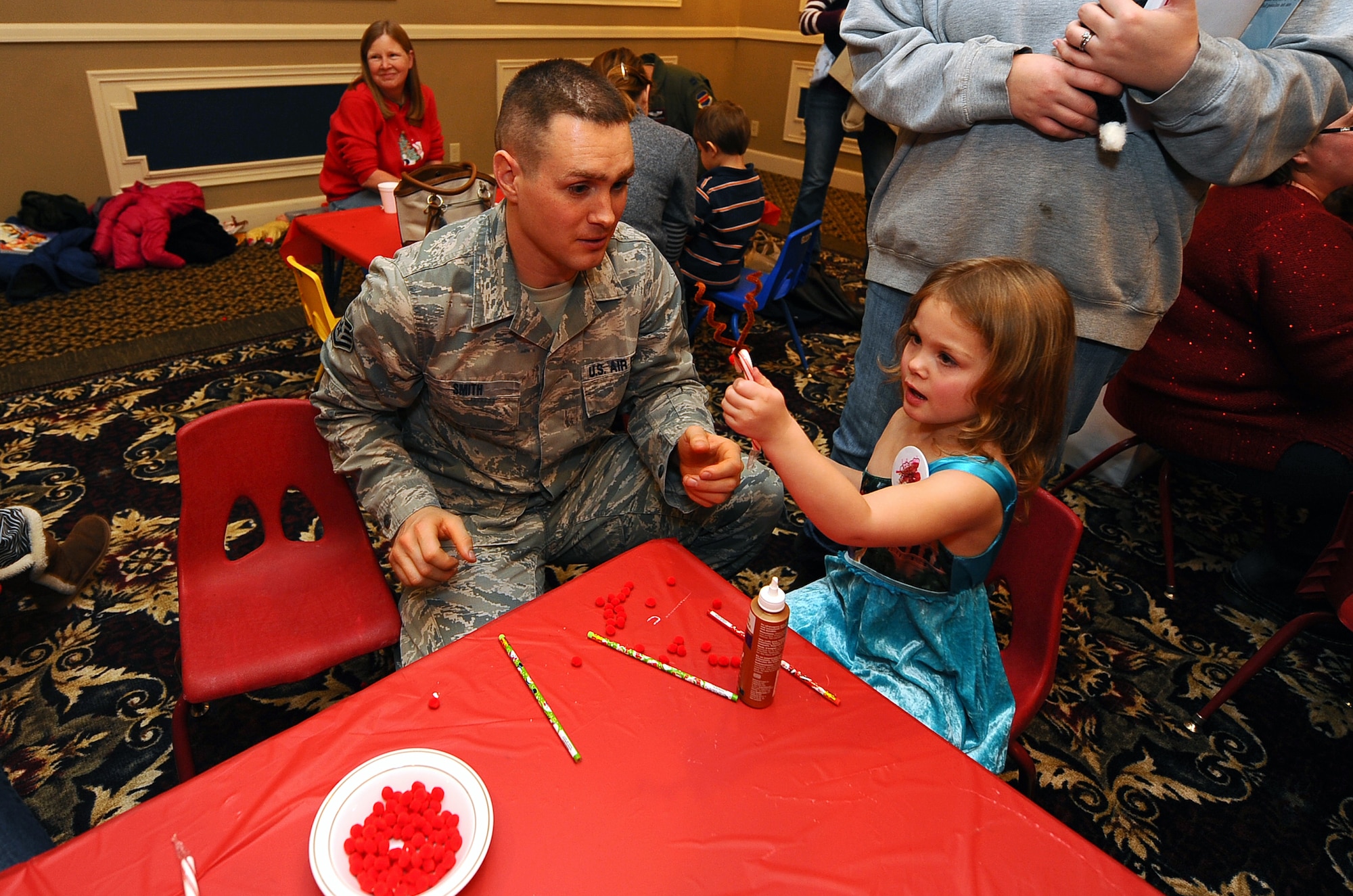 U.S. Air Force Staff Sgt. Cameron Smith, 55th Strategic Communication, and his three-year-old-daughter, Teagan, decorate a candy cane to look like one of Santa’s Reindeer while attending the Christmas Tree Lighting reception held at the Patriot Club on Offutt Air Force Base, Neb., Nov. 29.  In addition to foods and crafts children also had a chance to meet Santa Claus and be entertained by a magician.  (U.S. Air Force photo by Josh Plueger/Released)