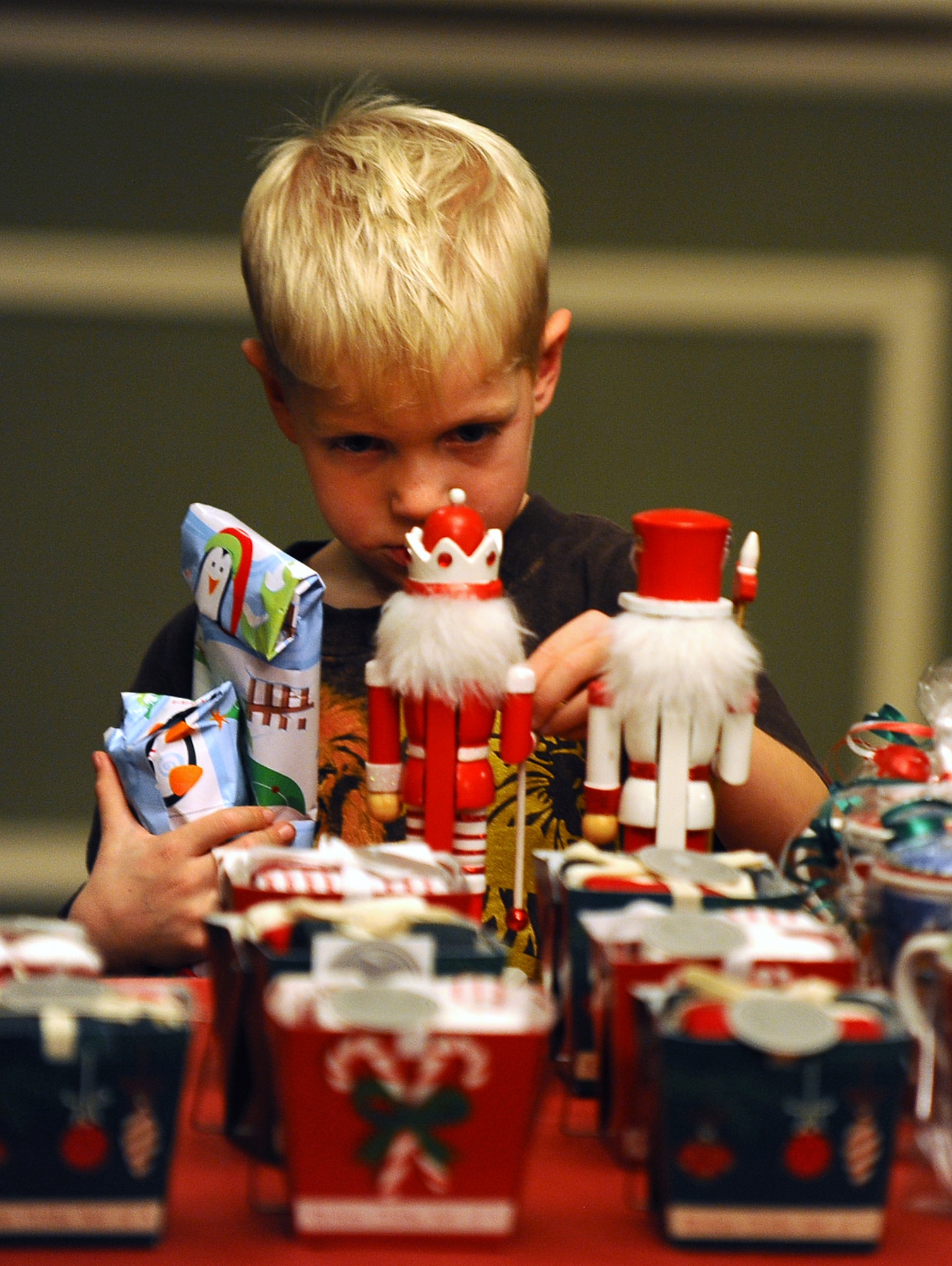 Five-year-old John Schatz, son of Master Sgt. Alicia Schatz, 55th Medical Operations Squadron, carefully looks through the “elf mart” merchandise to select a gift for his parents as part of the Christmas Tree Lighting Ceremony held at Offutt Air Force Base, Neb., Nov. 29.  The “Elf Mart” catered exclusively to child shoppers with all items for mom and dad costing one dollar.  Complimentary gift wrapping by Santa’s elves was also available.  (U.S. Air Force photo by Josh Plueger/Released)