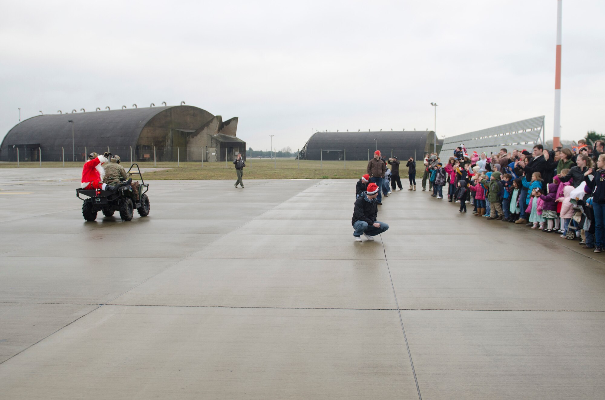 ROYAL AIR FORCE LAKENHEATH, England - Santa Claus, a North Pole native, waves to Team Lakenheath members from the backseat of an all-terrain vehicle driven by Staff Sgt. Anthony DeRoest, 56th Rescue Squadron pararescueman and native of Portland, Ore., Dec. 1, 2012. Claus teamed up with the 56th RQS HH-60G Pave Hawk to bring Christmas cheer to Team Lakenheath members. After being dropped off by 56th RQS, Claus proceeded to Hangar 7 where children were able to meet him and tell him what they wanted for Christmas. (U.S. Air Force photo by Staff Sgt. Stephen Linch)