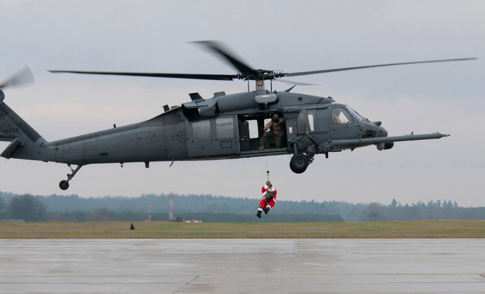 ROYAL AIR FORCE LAKENHEATH, England - Santa Claus, a North Pole native, is lowered to the ground from an HH-60G Pave Hawk by Tech. Sgt. Mike Morrison, 56th Rescue Squadron NCO in charge of standards and evaluations and native of Salisbury, Mo., Dec. 1, 2012. According to Claus, the 56th RQS's combat search and rescue capabilities, which allow it to execute all-weather search and rescue missions day or night including those in hostile environments, made it an ideal unit to team up with to deliver Christmas cheer. (U.S. Air Force photo by Staff Sgt. Stephen Linch)