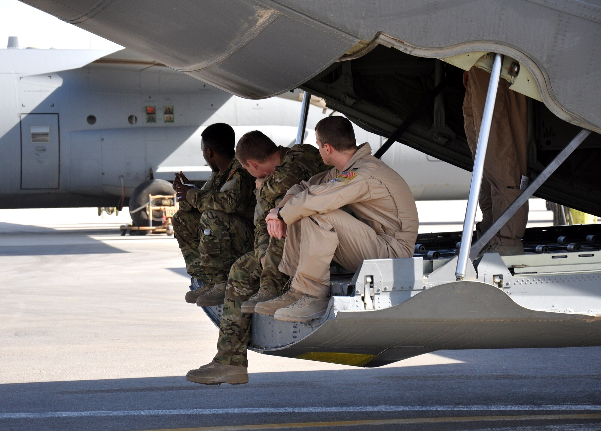 Senior Airmen Dan Simonsen and Marcus Wright, loadmasters, and Capt. Russell Neice, C-130J pilot, sit on the back of the aircraft parked on the ramp at Kandahar Airfield in between missions Nov. 15. They are assigned to the 772nd Expeditionary Airlift Squadron and are deployed from Dyess Air Force Base, Texas. (U.S. Air Force photo/Capt. Tristan Hinderliter) 