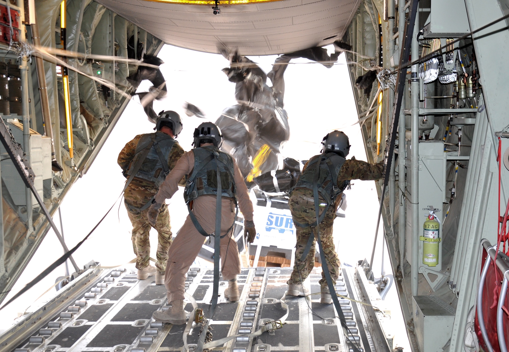 Senior Airman Dan Simonsen, Senior Master Sgt. Steve Martin and Senior Airman Marcus Wright, loadmasters with the 772nd Expeditionary Airlift Squadron, perform a Low Cost, Low Altitude airdrop from the back of a C-130J in southwest Afghanistan Nov. 15. They are deployed from Dyess Air Force Base, Texas. (U.S. Air Force photo/Capt. Tristan Hinderliter)