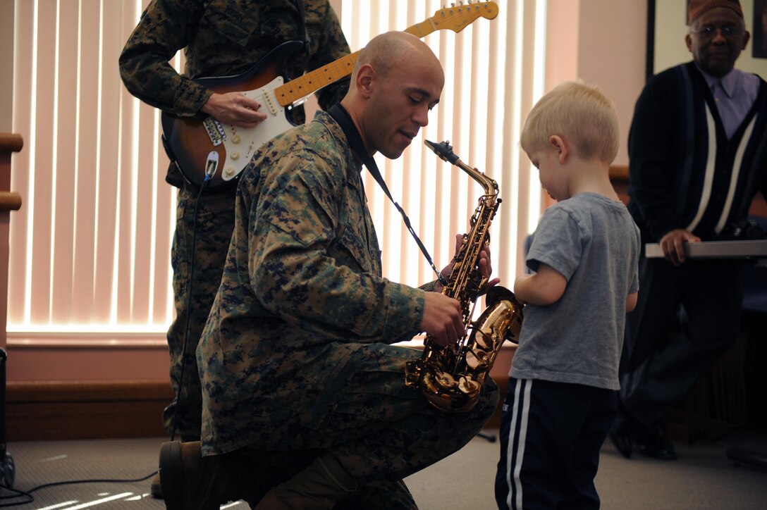 Staff Sgt. Eric Kyne, saxophone, Marine Corps Base Quantico Band Jazz Ensemble, shows Jack, 3, how the saxophone works during the Books and Breakfast Friday at the base library. The band played during the reading of “Mamma Don’t Allow” and afterwards so the children could dance.