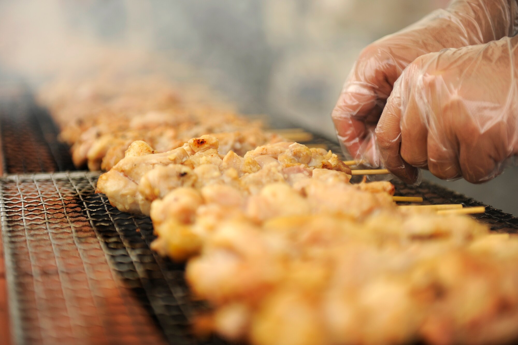 A food vendor prepares garlic chicken skewers at the Tinsel Town holiday festival on Kadena Air Base, Japan, Dec. 1, 2012. The event featured roughly 65 separate vendors, organizations, crafters and volunteers from on- and off-base facilities, promoting a positive relationship with service members and the local community. (U.S. Air Force photo/Senior Airman Maeson L. Elleman)