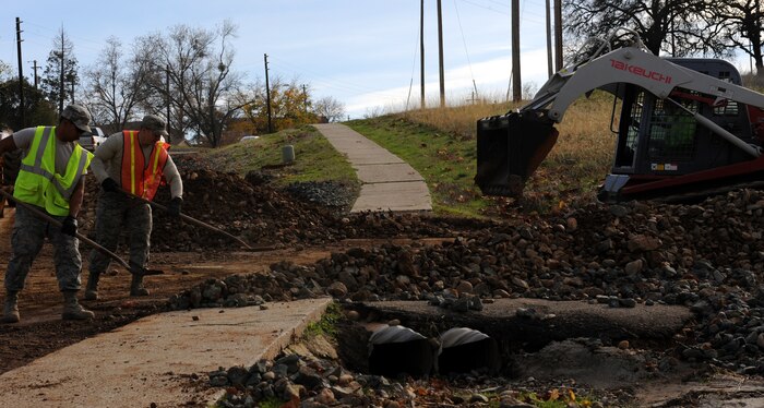 Airmen from the 9th Civil Engineer Squadron remove debris from a bridge off Camp Beale Highway at Beale Air Force Base, Calif., Dec. 3, 2012. The 9th CES removed more than 60 yards of debris after heavy rainstorms caused wide spread flooding on base. (U.S. Air Force photo by Airman 1st Class Robert Cummings/Released)      