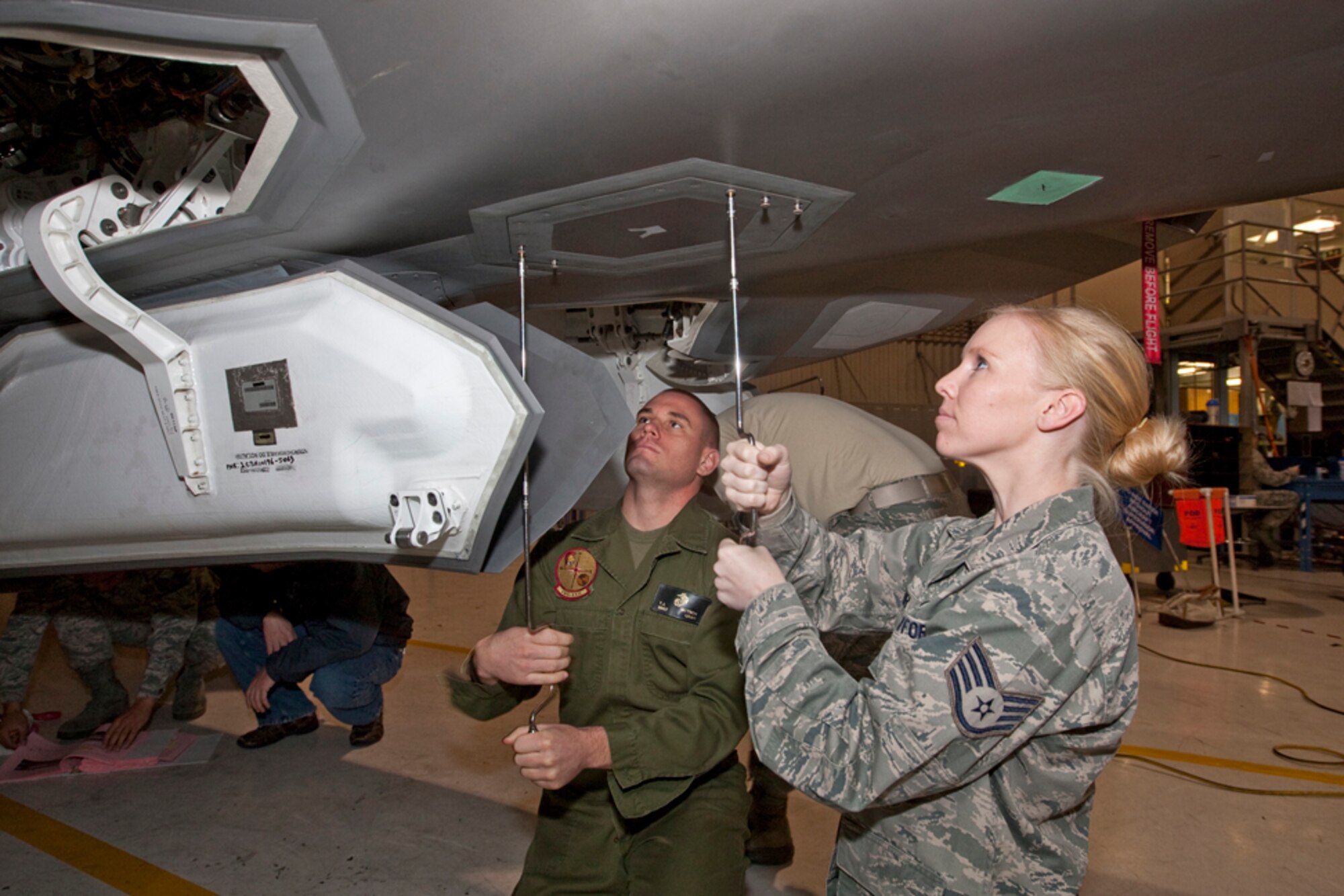 Staff Sgt Brittney Lehr, 412th Aircraft Maintenance Squadron JSF, and Marine Staff Sgt.Thomas Mitsch, Marine Tiltrotor Operational Test and Evaluation Squadron 22, work to remove a panel on an F-35. For more than 18 months, developmental test personnel from the F-35 Integrated Test Force have been responsible for training operational maintainers from the 31st Test and Evaluation Squadron and Marine Tiltrotor Operational Test and Evaluation Squadron 22; the marines who will maintain the F-35B Short Takeoff Vertical Landing variant. Seventy-six personnel have successfully completed the program with 15 maintainers currently participating.