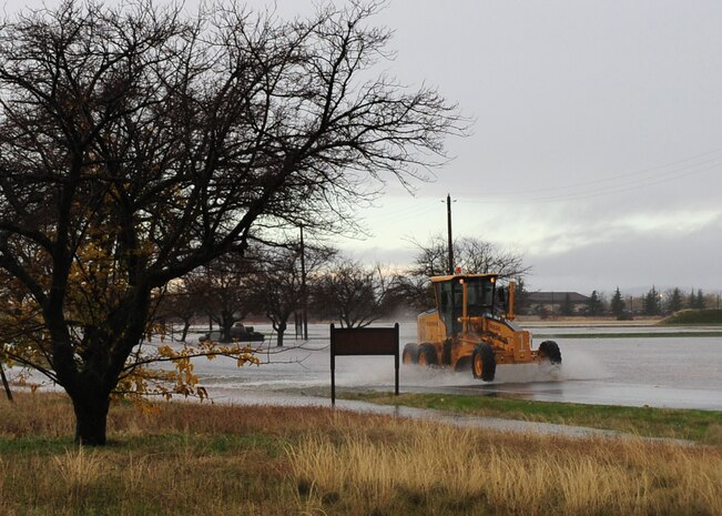 A piece of heavy equipment from the 9th Civil Engineer Squadron is driven through flooding next to the range on Doolittle Dr. at Beale Air Force Base, Calif., Dec. 2, 2012. The 9th and 940th Civil Engineer Squadrons responded to clear roads of debris and fix downed power lines throughout base. (U.S. Air Force photo by Senior Airman Shawn Nickel/Released)
