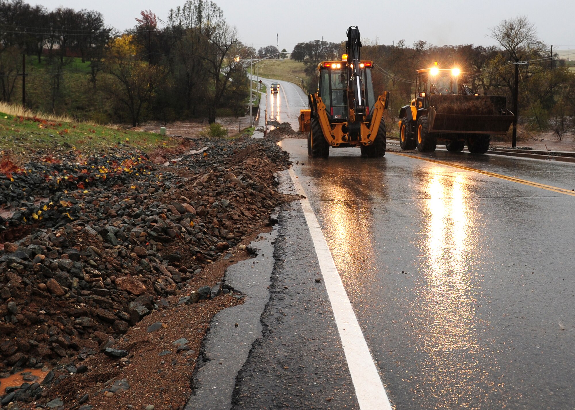 Airmen from the 9th and 940th Civil Engineer Squadrons operate heavy equipment to clear the bridge on Camp Beale Hwy. after a storm flooded rocks onto the roadway and water flooded over the crossing Dec. 2, 2012 at Beale Air Force Base, Calif. Several roadways between main base and housing flooded. (U.S. Air Force photo by Senior Airman Shawn Nickel/Released)