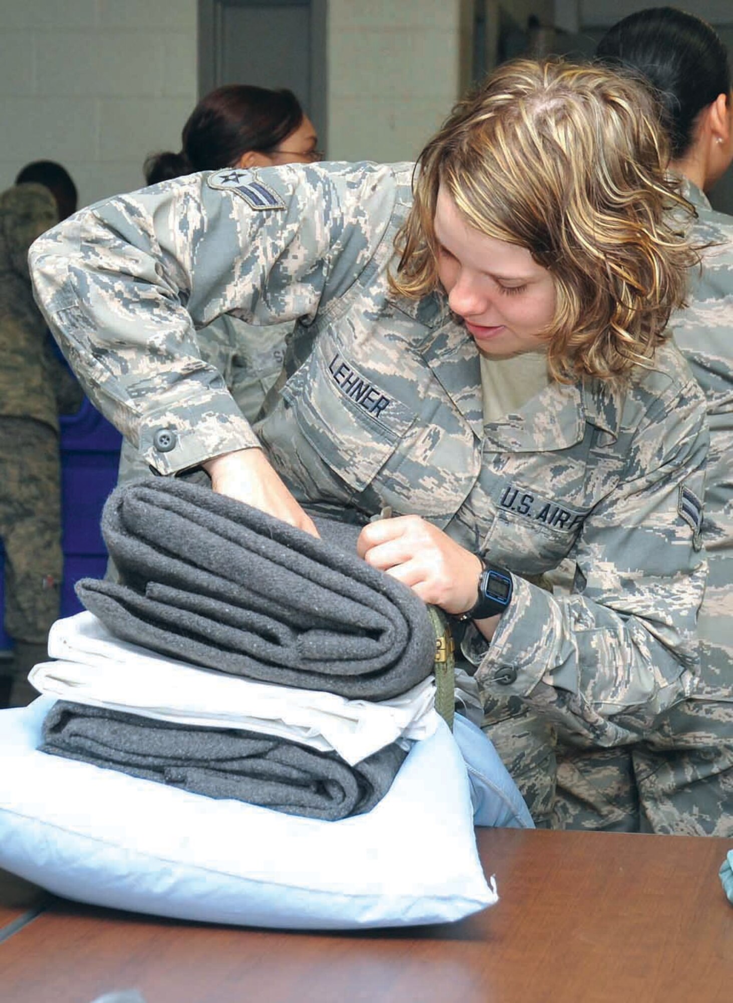 Airman 1st Class Taryn Lehner bundles ‘Newbie Bundles’ consisting of blankets and linens for Trainees and Airmen arriving to the 324th Training Squadron. (U.S. Air Force Photo/Alan Boedeker)