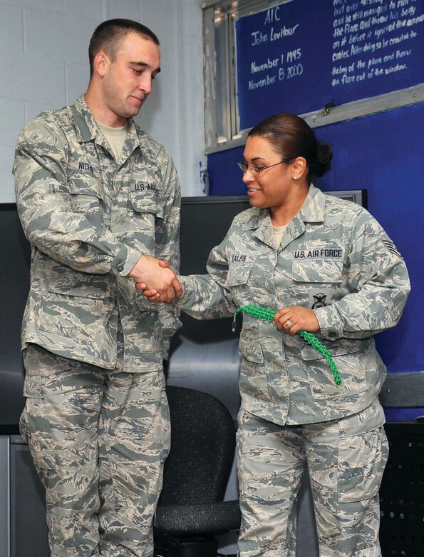 Staff Sgt. Sales removes the Green Rope from Airman Basic Cory Nichols signifies his relinquishing additional duties as he is ready to move on to technical school. (U.S. Air Force Photo/Alan Boedecker)