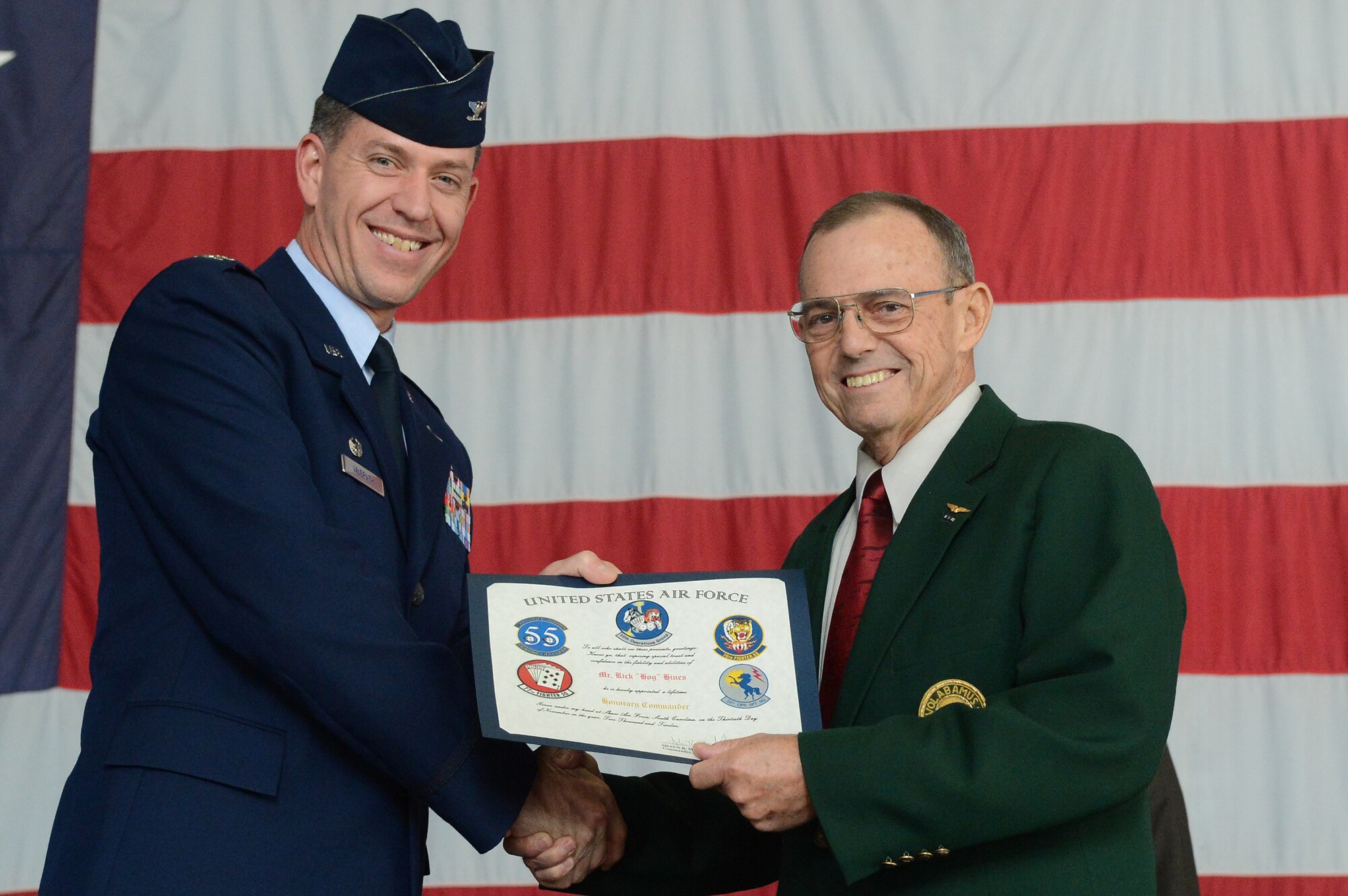 U.S. Air Force Col. Shaun McGrath, 20th Operations Group commander, awards Rick Hines the title of lifetime honorary commander in Hangar 1200, Shaw Air Force Base, S.C., Nov. 30, 2012.  The honorary commander program is intended to strengthen the bonds between Shaw and its Sumter neighbors.  (U.S. Air Force photo by Airman Nicole Sikorski/Released)