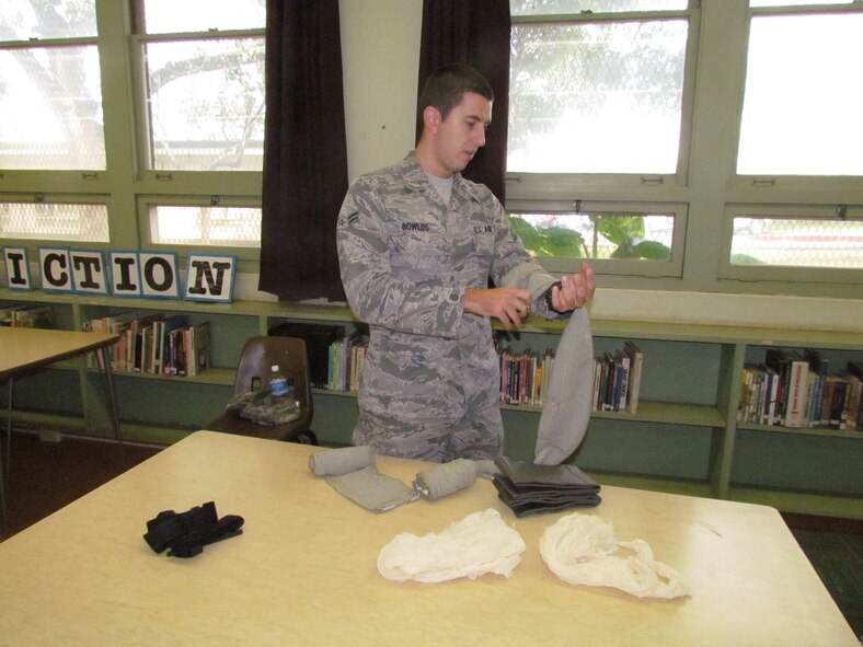 Airman 1st Class Christopher Bowlds of the 15th Medical Group at Joint Base Pearl Harbor-Hickam, Hawaii, shows students how to provide medical care to a patient during a lesson Nov. 29 at Radford High School. The activity provided students with real-life experience and training in the medical skills needed to effectively care for a patient. (U.S. Navy photo by Don Robbins)

