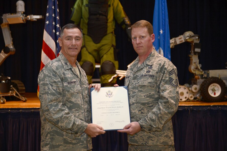 Col. Barton Barnhart, Air Force Central Command director of installation, presents Chief Master Sgt. Jerry Shelton, AFCENT explosive ordnance disposal manager, his certificate of retirement at Shaw Air Force Base, S.C., Nov. 30, 2012. Shelton is scheduled to officially retire March 1, 2013.