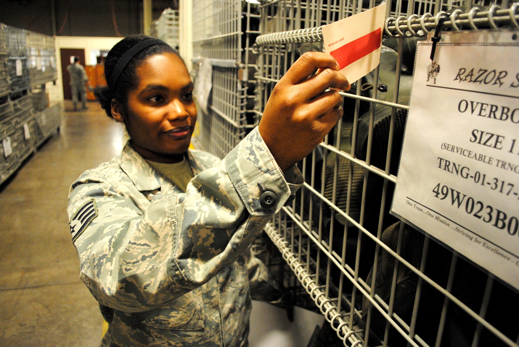 Staff Sgt. Adrian Jensen, an individual protective equipment NCO with the 319th Logistics Readiness Squadron, verifies information on an inspection tag for a cage filled with oversized rubber boot covers Nov. 26, 2012, at the 319th LRS mobility equipment depot on Grand Forks Air Force Base, N.D.  Along with keeping inventory of equipment, Jensen also periodically inspects the items to ensure they are clean and serviceable for training scenarios and real-world deployments. (U.S. Air Force photo/Senior Airman Luis Loza Gutierrez) 