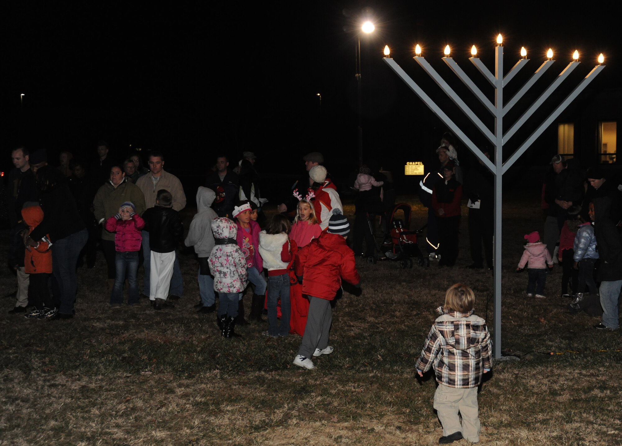 Families gather around the Menorah after it’s lit during the Christmas Tree and Menorah Lighting Ceremony at Chapel One, Nov. 29, 2012. The lighting of the tree and menorah is an annual event that consists of singing, menorah and tree lighting, prayer and a visit from Santa and Mrs. Claus. (U.S. Air Force photo/Airman 1st Class Erin O’Shea)