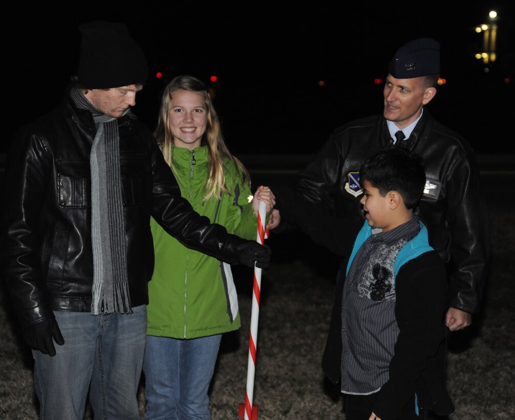 Col. Bill Knight, 11th Wing/Joint Base Andrews commander, and deployed spouse family members pull the candy cane switch to light the Christmas Tree and the menorah at Chapel One, Nov. 29, 2012. The lighting of the tree and menorah is a yearly event that consists of singing, menorah and tree lighting, prayer and a visit from Santa and Mrs. Claus. (U.S. Air Force photo/Airman 1st Class Erin O’Shea) 
