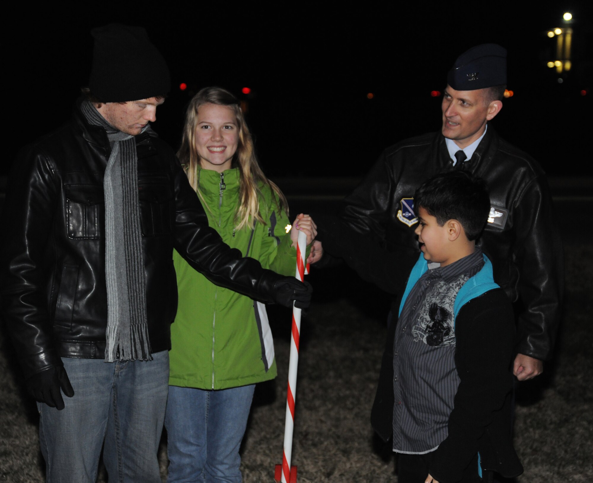 Col. Bill Knight, 11th Wing/Joint Base Andrews commander, and deployed spouse family members pull the candy cane switch to light the Christmas Tree and the menorah at Chapel One, Nov. 29, 2012. The lighting of the tree and menorah is a yearly event that consists of singing, menorah and tree lighting, prayer and a visit from Santa and Mrs. Claus. (U.S. Air Force photo/Airman 1st Class Erin O’Shea) 
