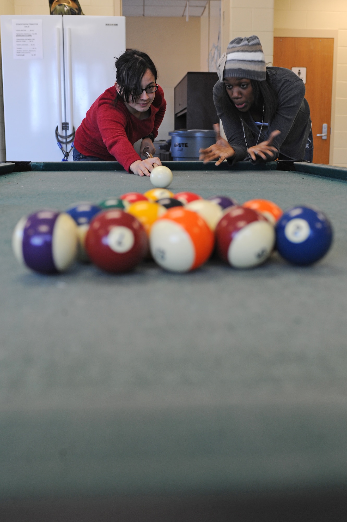 U.S. Air Force Airman 1st Class Andrea Spanjer, 4th Aerospace Medicine Squadron bioenvironmental engineer, demonstrates how to perform a break to Airman 1st Class Adrienne Quinn, 4th Medical Support Squadron health services technician, during a game of pool at the Airman’s Center on Seymour Johnson Air Force Base, N.C., Dec. 1, 2012. The Airman’s Center contains pool tables, air hockey and foosball tables for recreational use. (U.S. Air Force photo/Airman 1st Class John Nieves Camacho/Released)